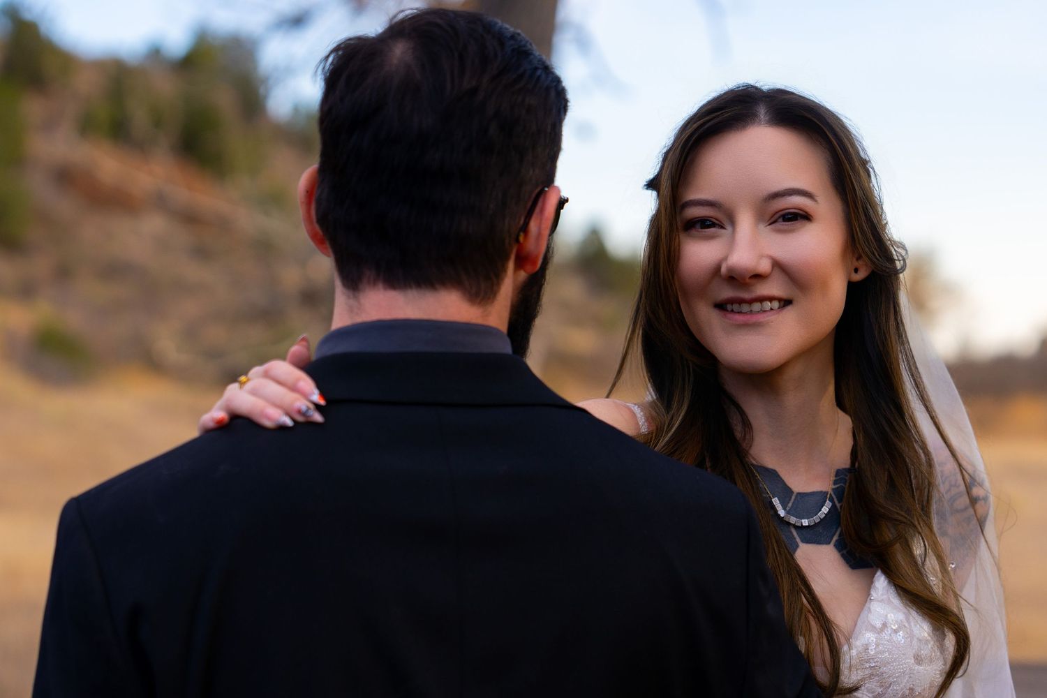 Couple embracing outdoors during sunset with mountains in the background.