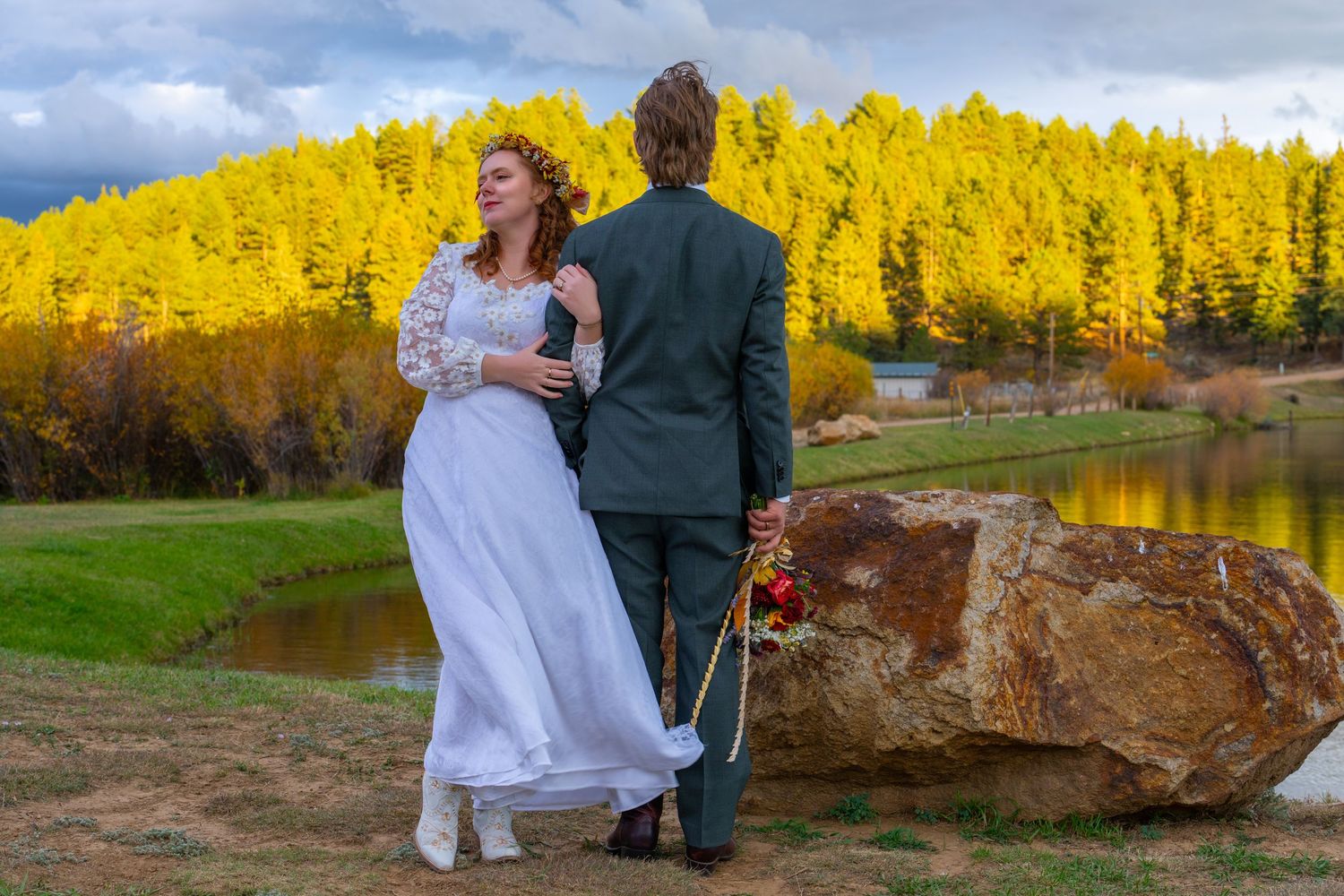 Wedding couple sitting on rocks with vibrant yellow canola fields in the background.
