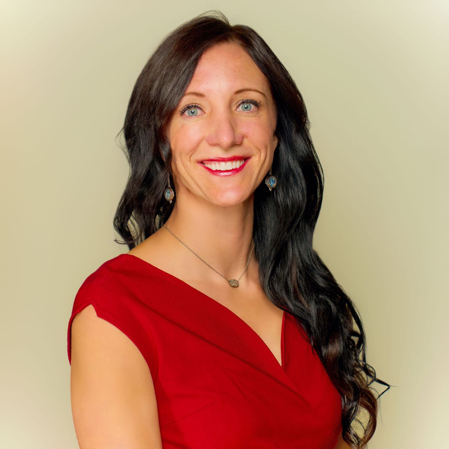 Professional headshot of someone in a red dress against neutral background.