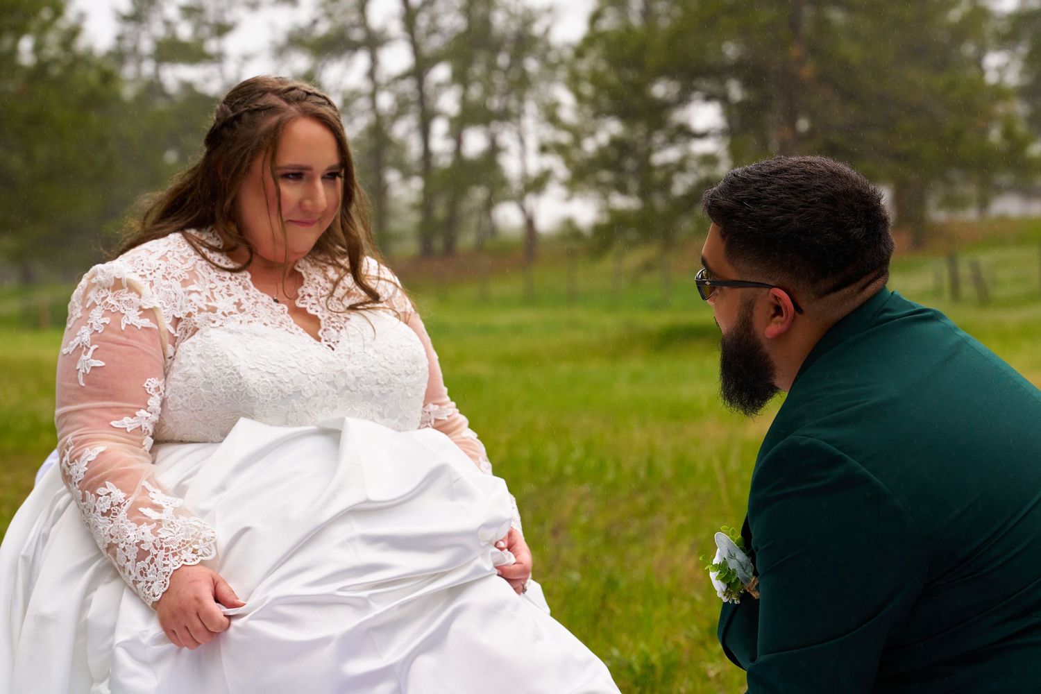 Wedding couple sharing an intimate moment together in a lush green field.