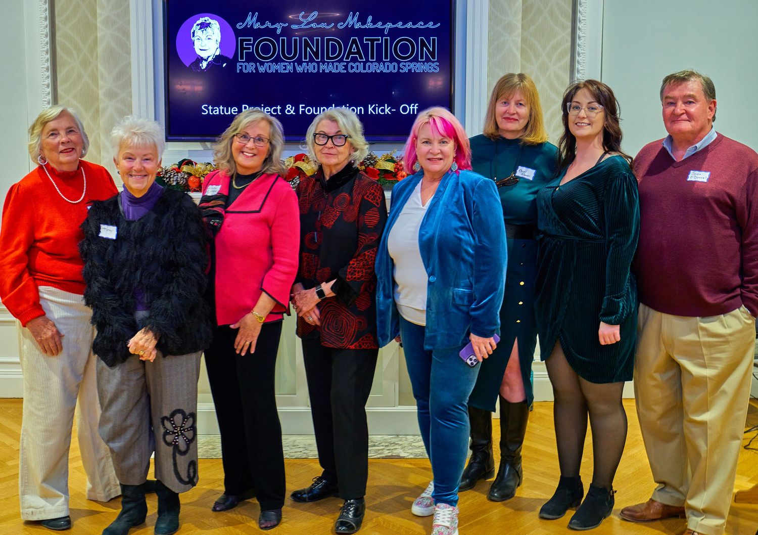 Group photo of organization members wearing colorful attire at a formal event.