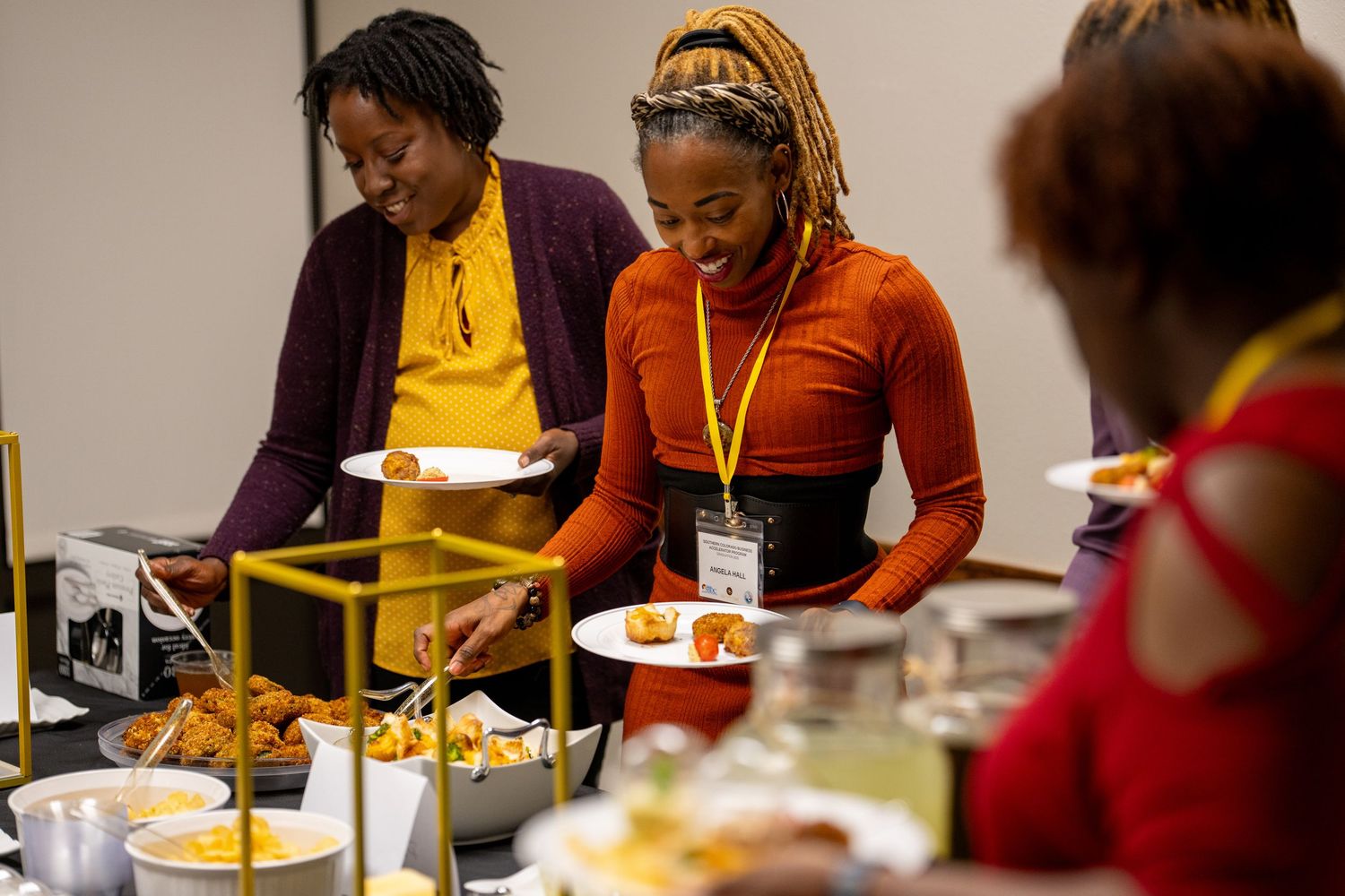 Conference attendees serve themselves at a buffet line with various food options.