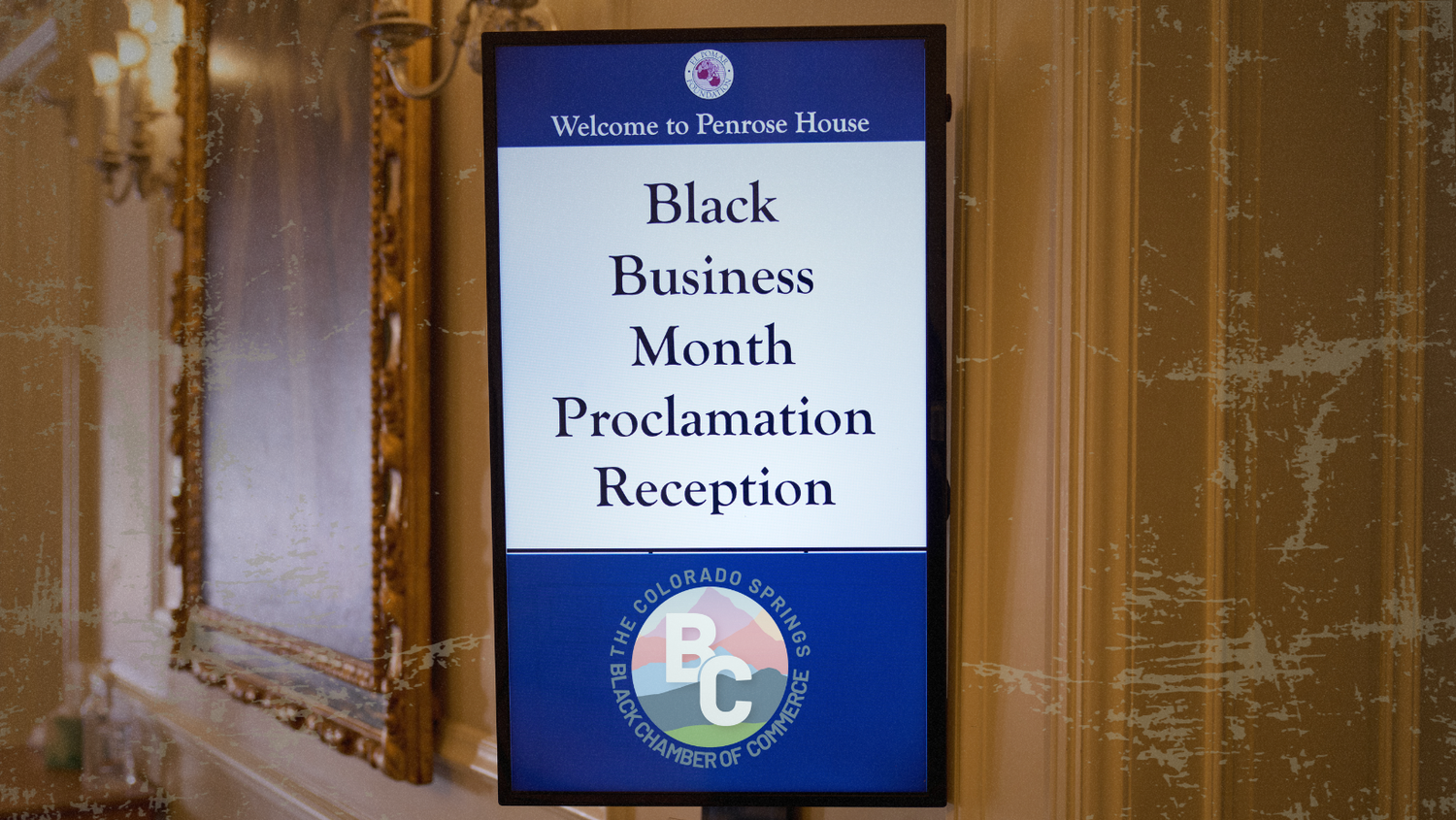 Blue and white sign displaying 'Black Business Month Proclamation Reception' with decorative border and seal.