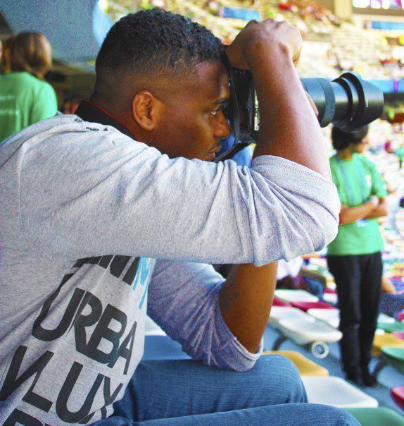 Photographer with telephoto lens capturing action at sporting event.