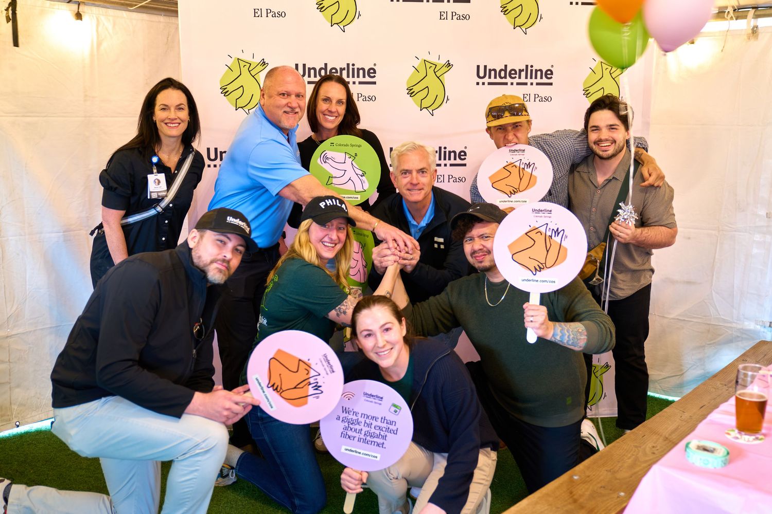 Group of people posing with branded circular signs at a business event.