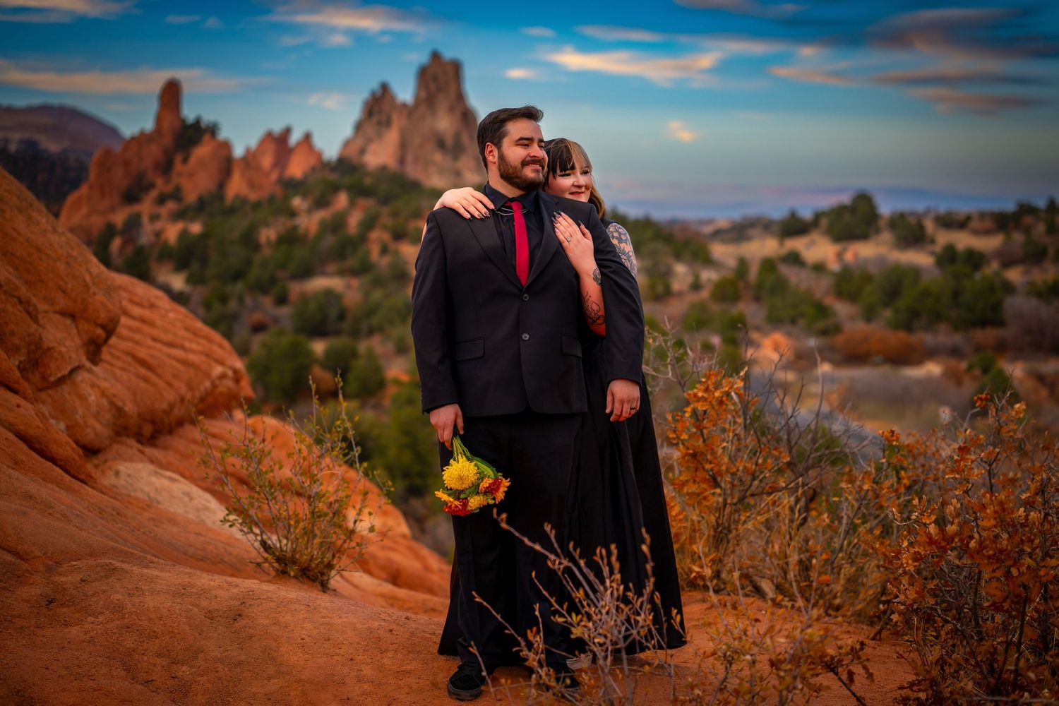 Scenic panoramic view of red rock formations at sunset with desert vegetation in Arches National Park.