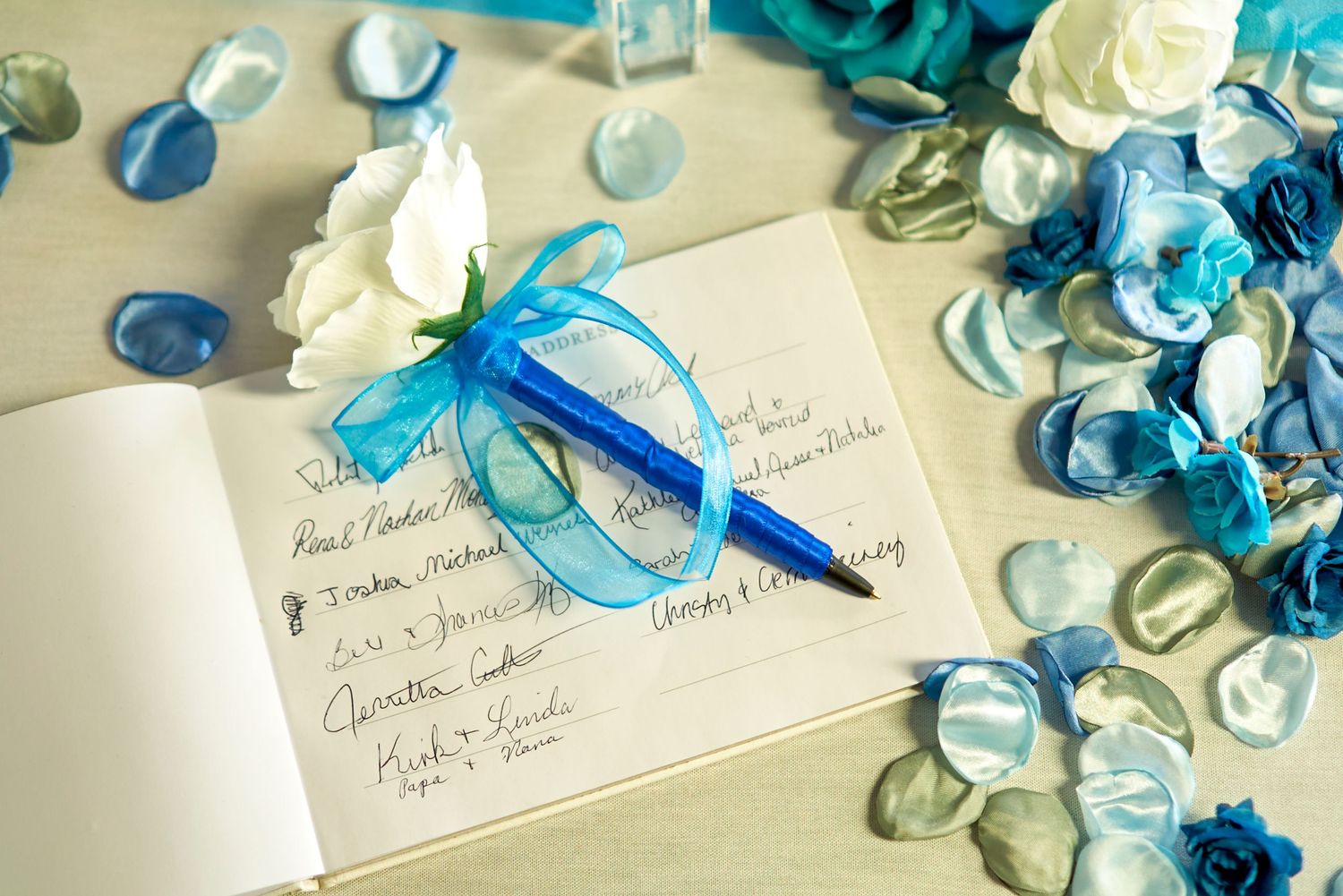Guest book page decorated with blue and white floral accents and a blue pen.