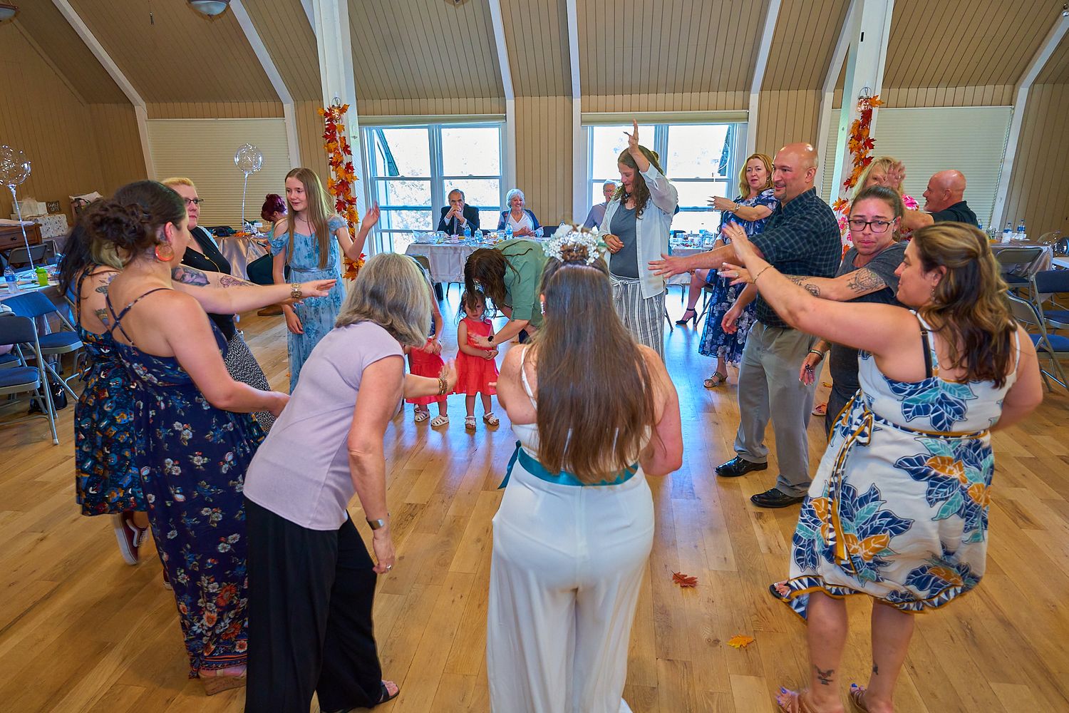 Wedding reception dance party in a bright wooden-floored venue.