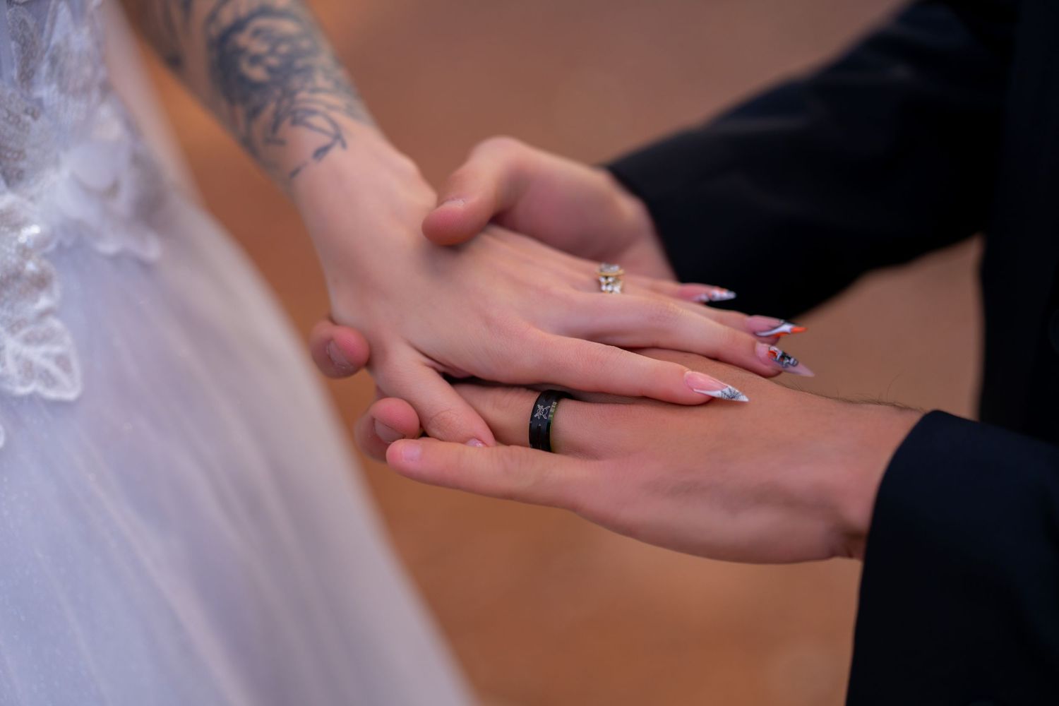 Close-up of hands exchanging wedding rings during a ceremony on a wooden surface.