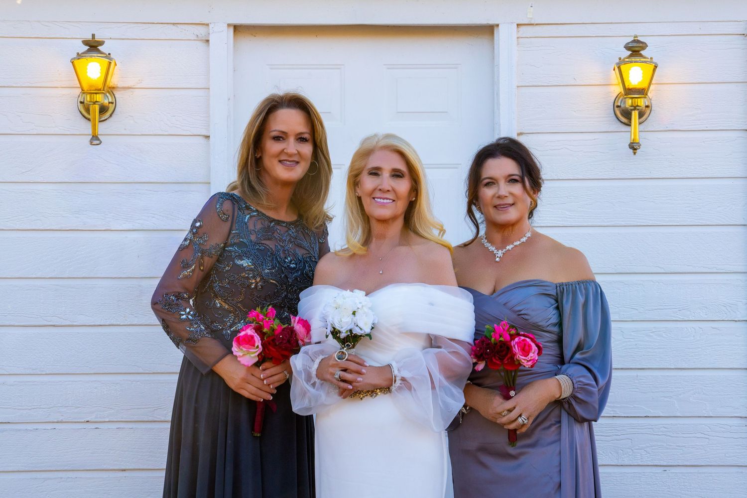 Wedding party members pose together in front of a white wall with yellow lanterns.