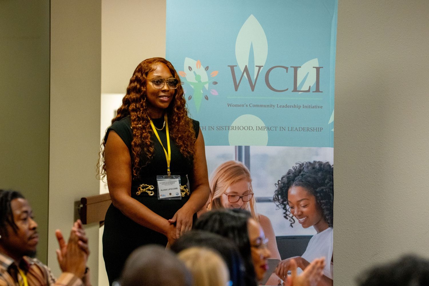 A speaker stands at a podium during a WCLI conference presentation.