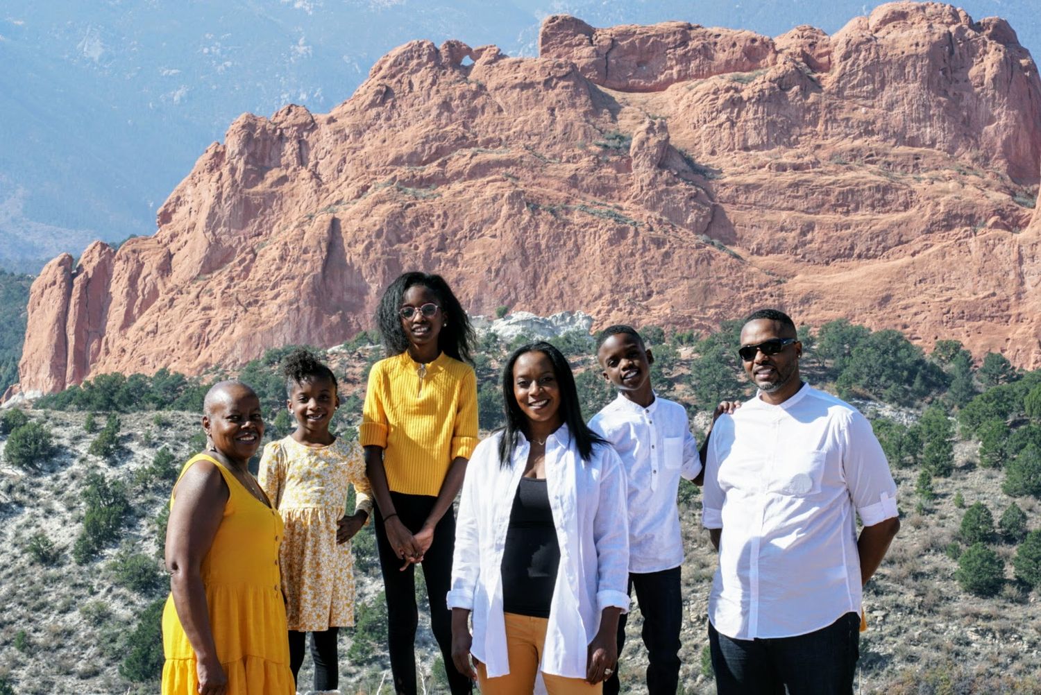 Family group portrait at Garden of the Gods with striking red rock formations in the background.