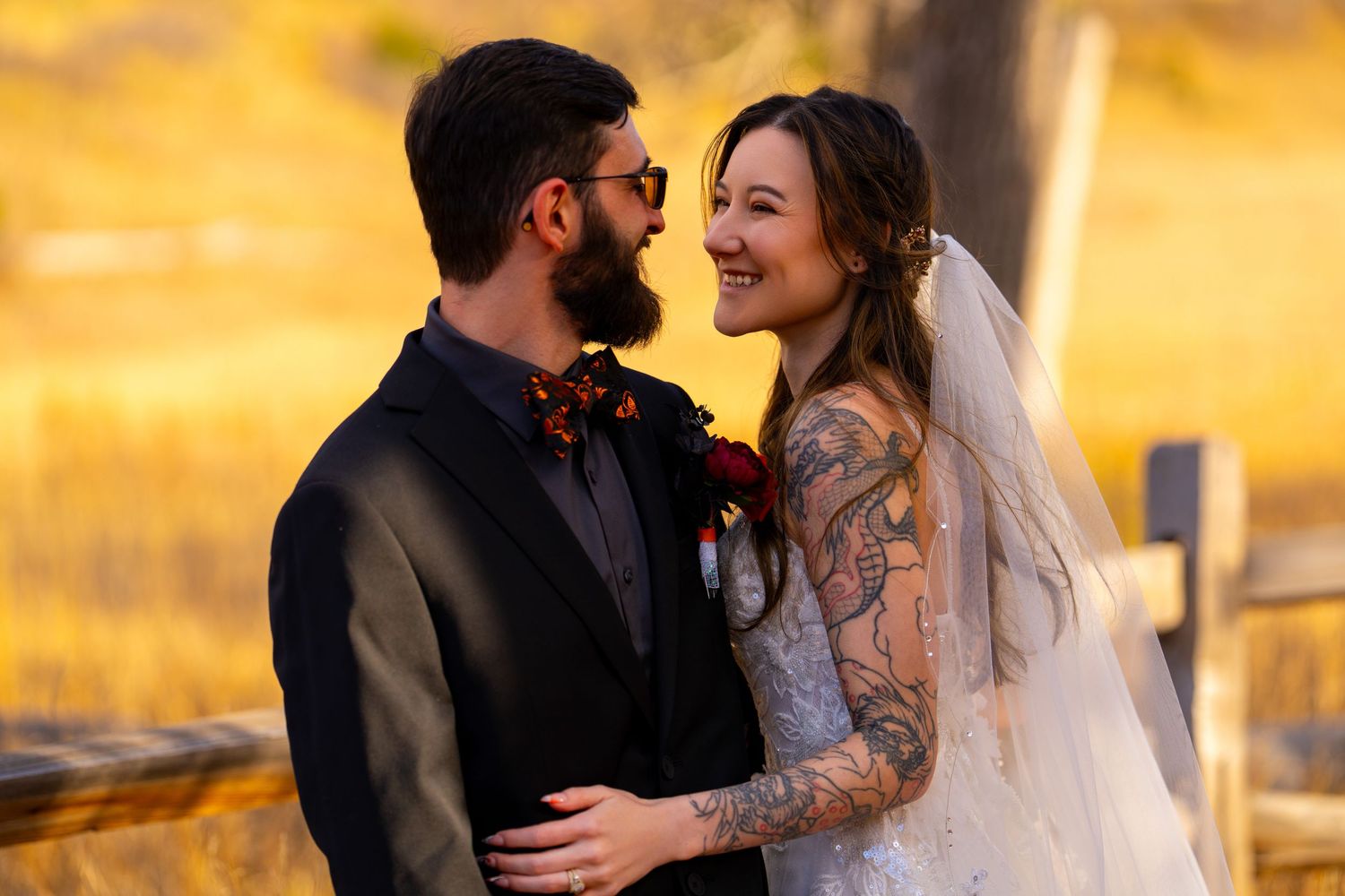 A happy couple shares a joyful moment on their wedding day against a warm golden sunset background.