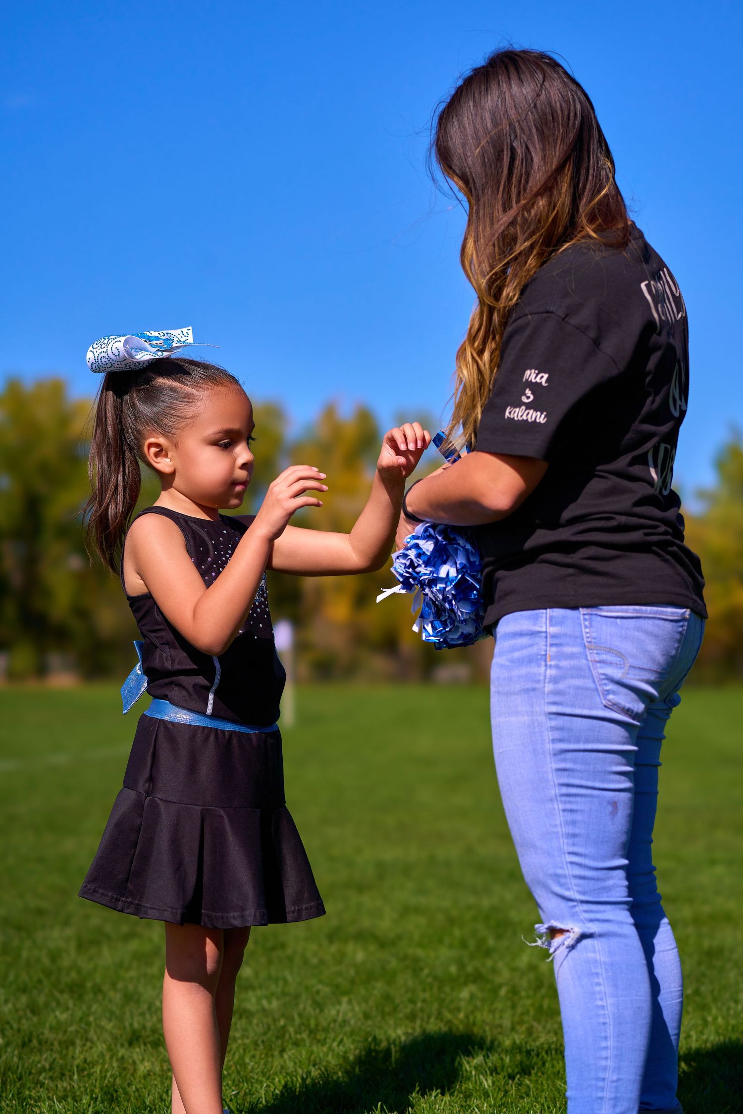 A cheerleader practice session taking place on a sunny day in an outdoor field.