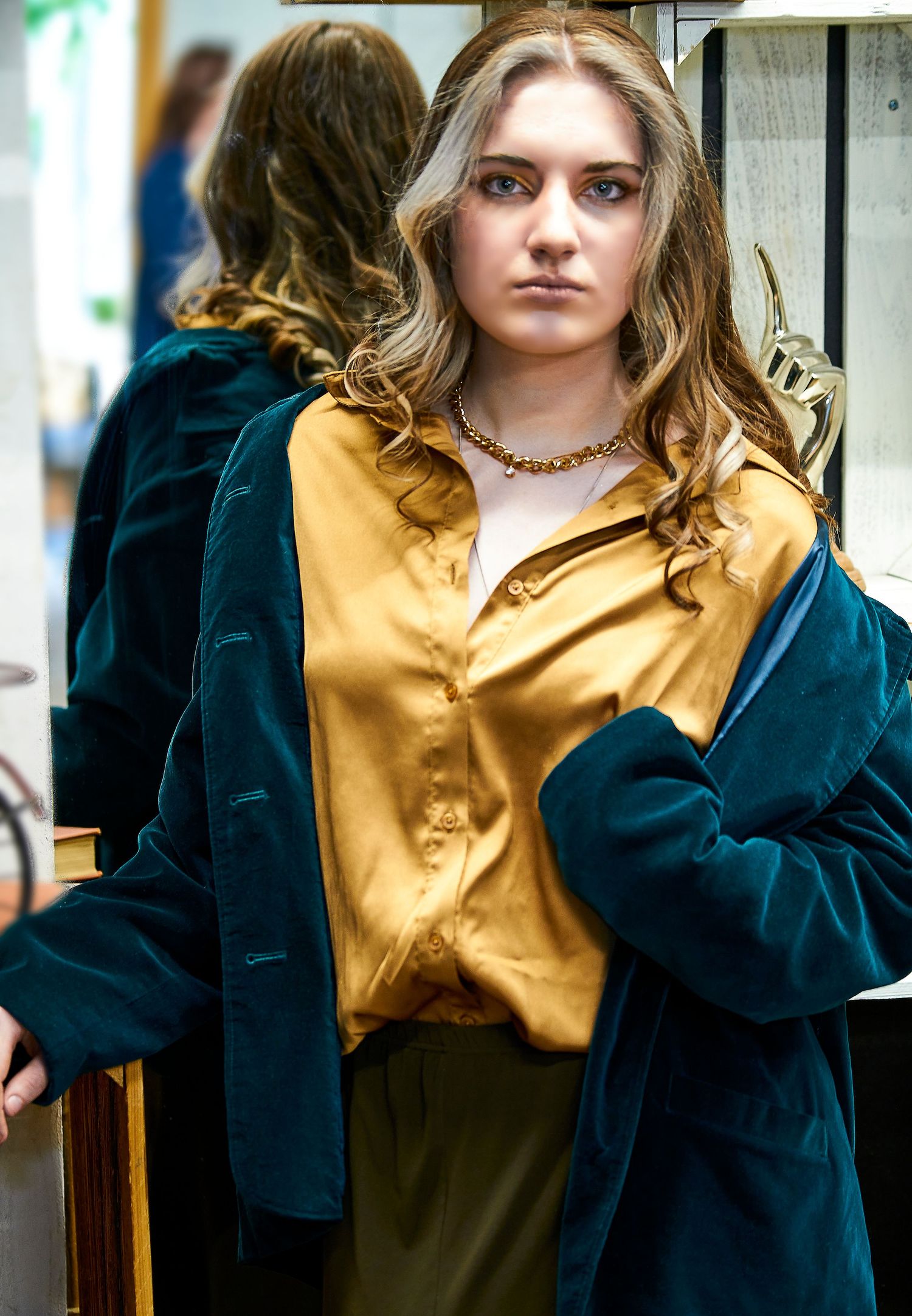 Stylish look featuring gold silk blouse and teal velvet jacket with statement necklace.