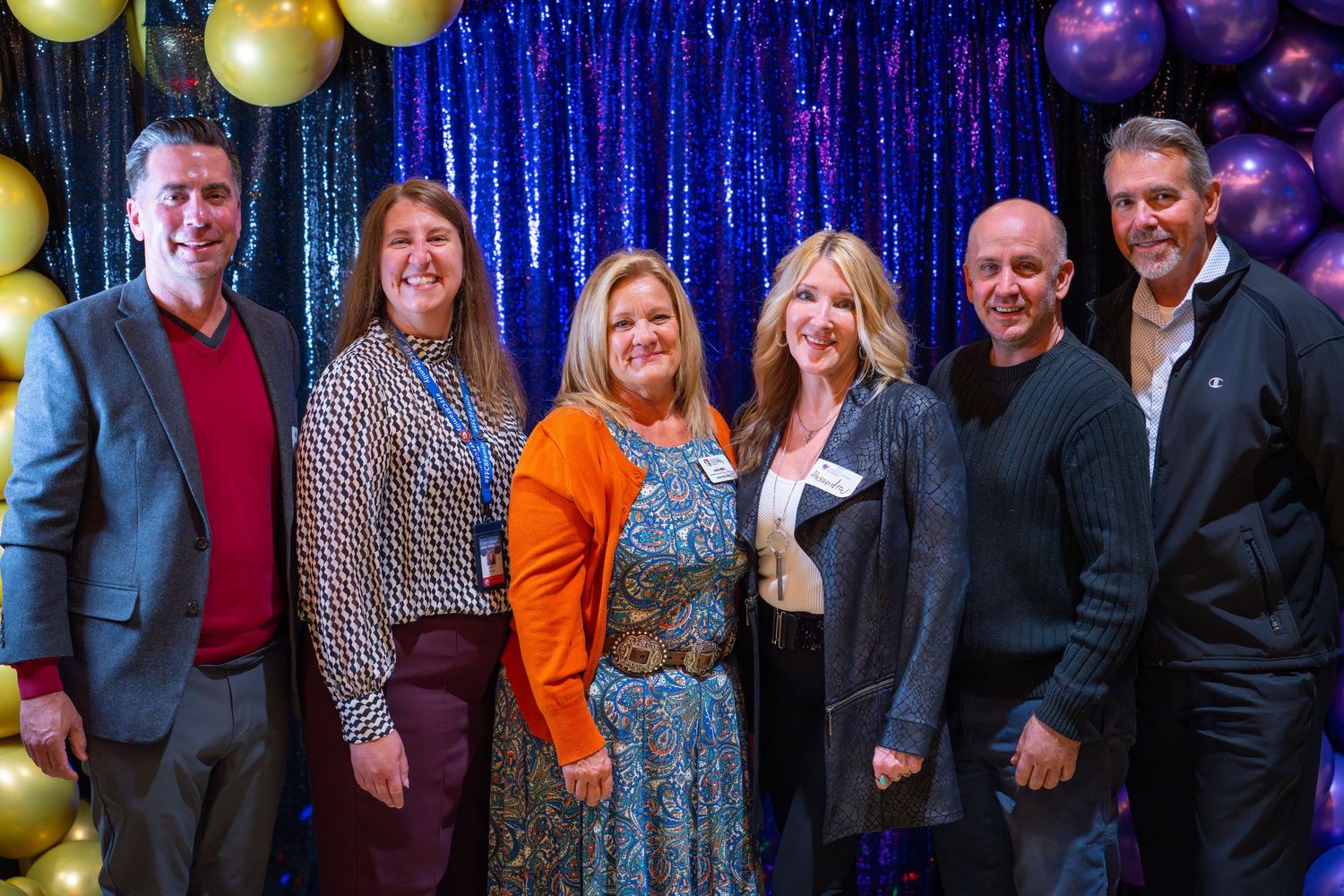 Group of seven professionals smiling at COS City Hub networking event with balloon decor.