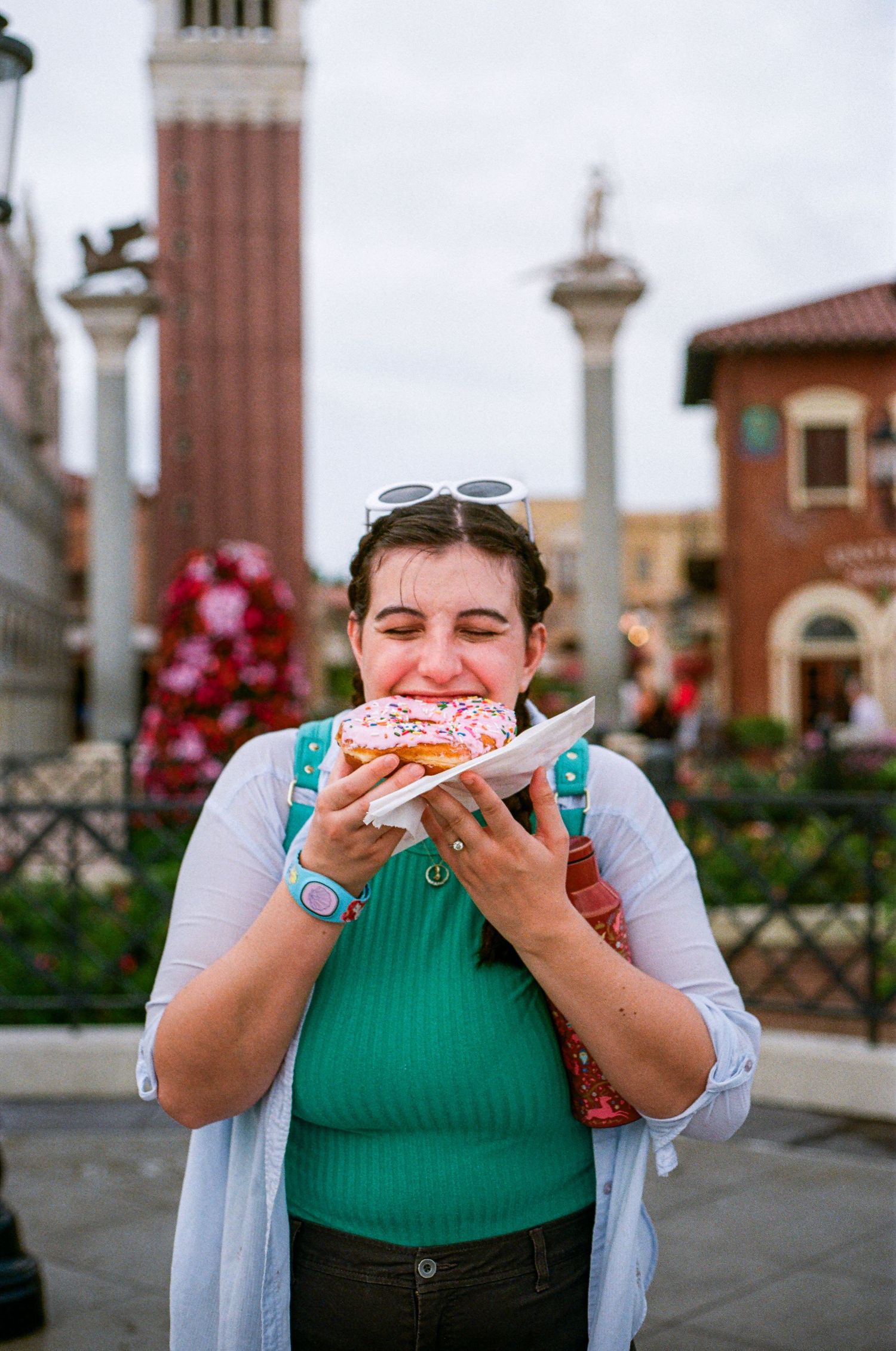 Person enjoying a slice of pizza outdoors near classic architecture and columns.