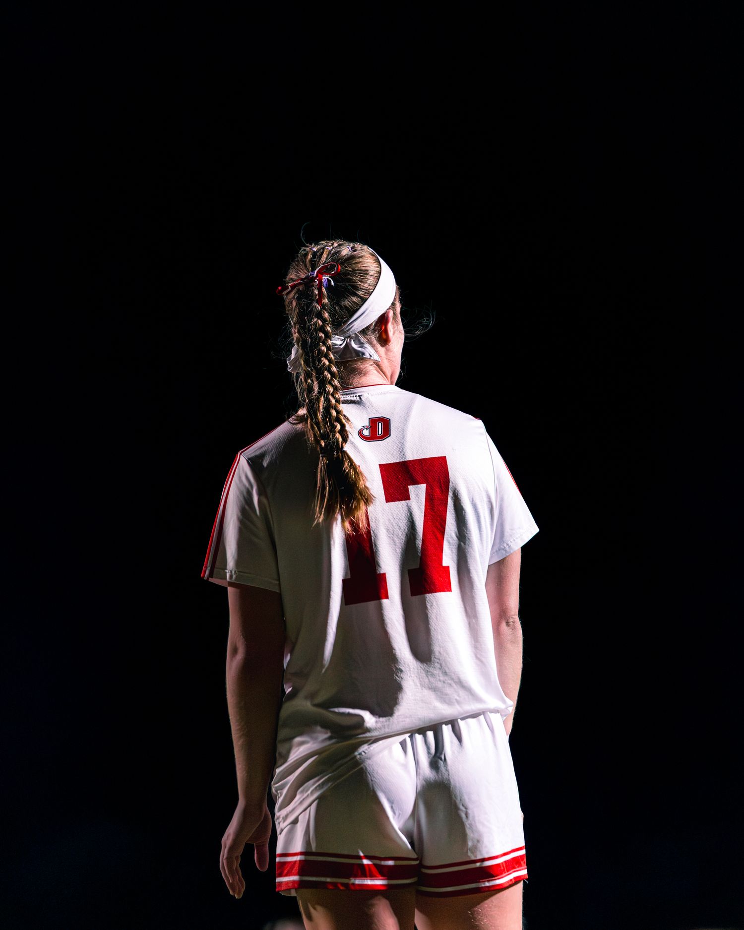 Soccer player wearing white jersey with number 4 viewed from behind during a game on dark background.