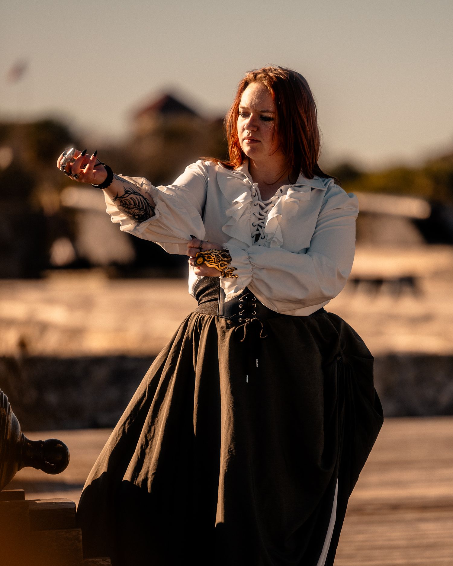 A person in historical costume poses dramatically at sunset.