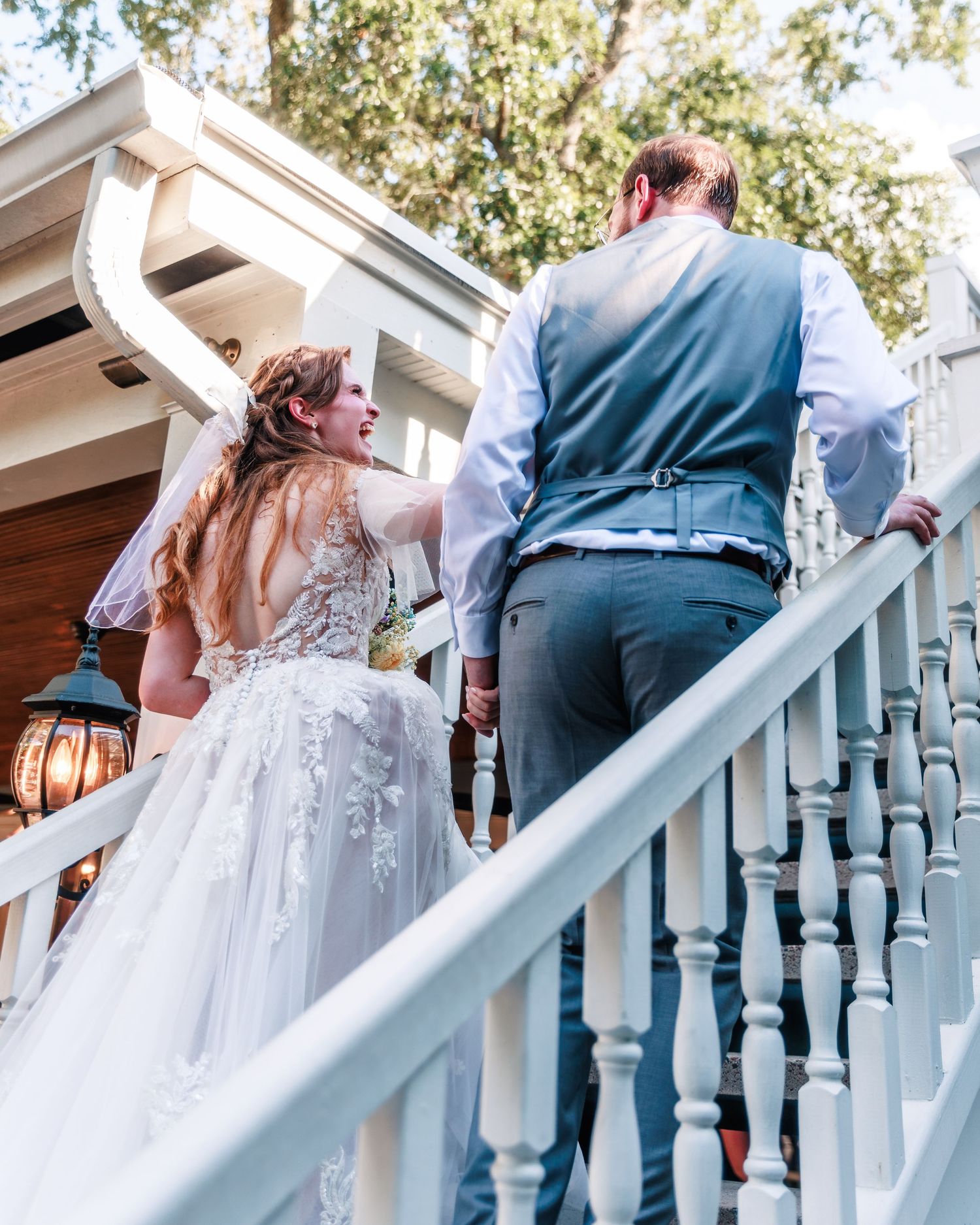 Bride and groom ascending blue stairs at an outdoor wedding venue.