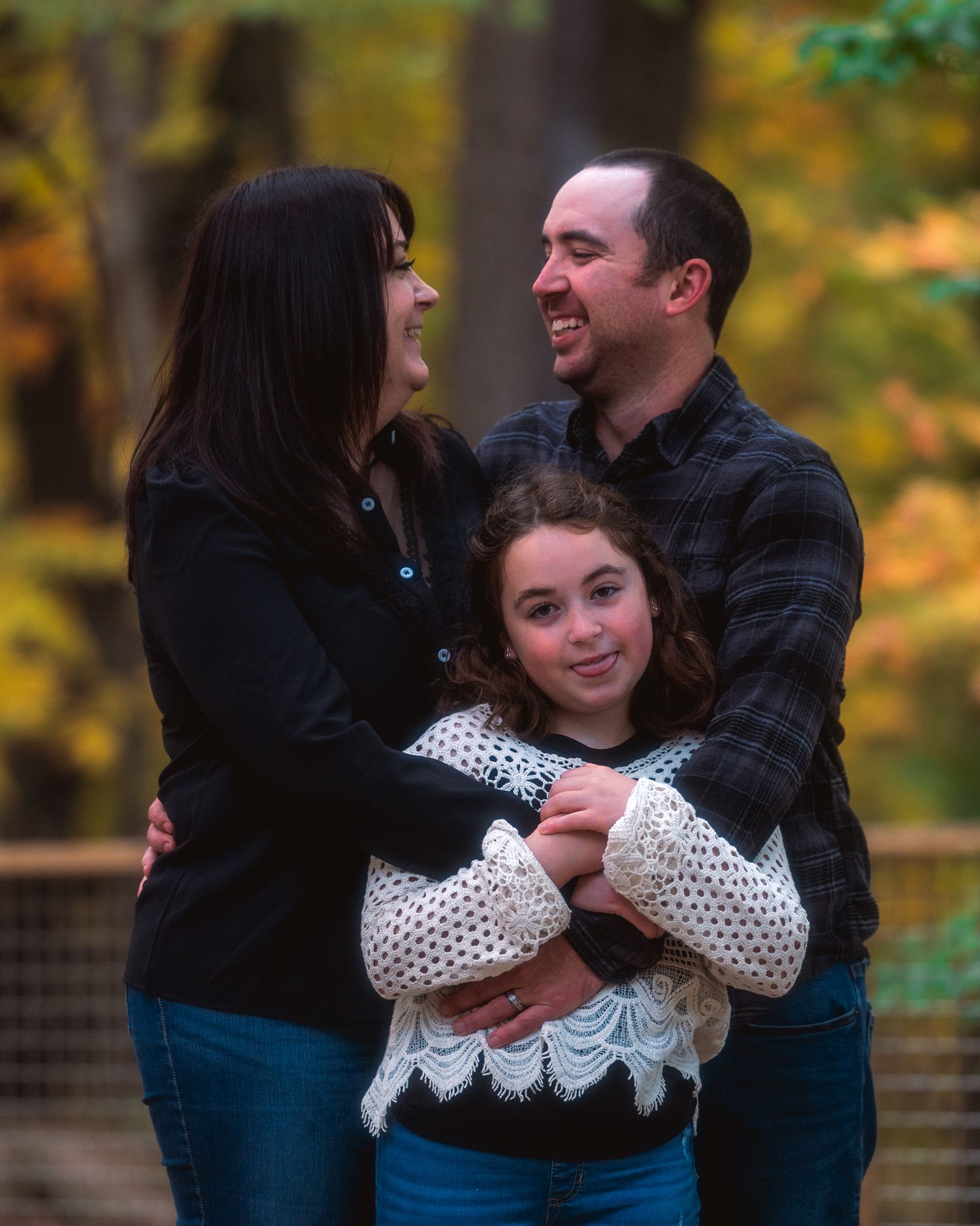 A family shares tender moments in a series of candid photos taken outdoors during autumn with fall foliage in the background.