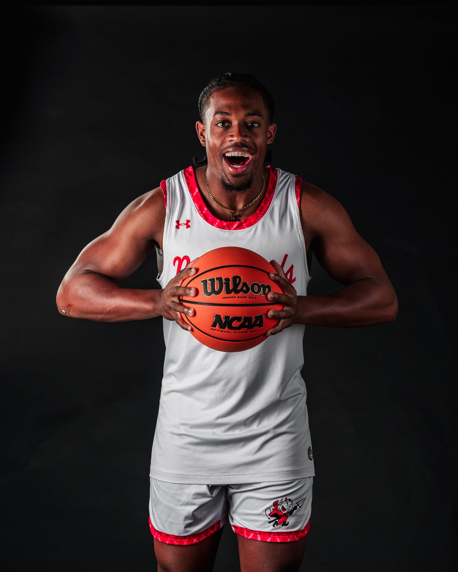 Basketball player in white jersey holds Wilson basketball against dark background in dramatic sports portrait series.