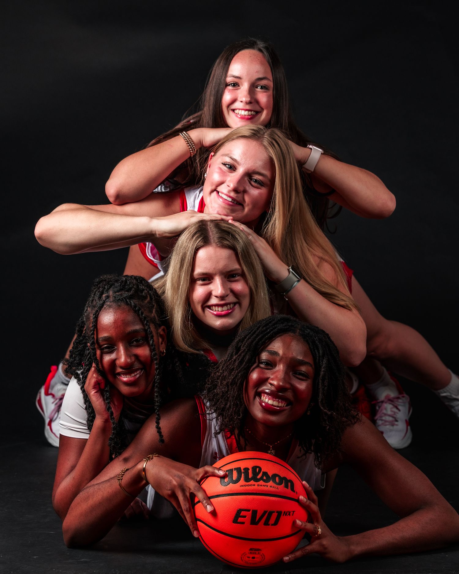 Group of friends pose playfully with red football in a series of candid black and white studio photos against dark background.