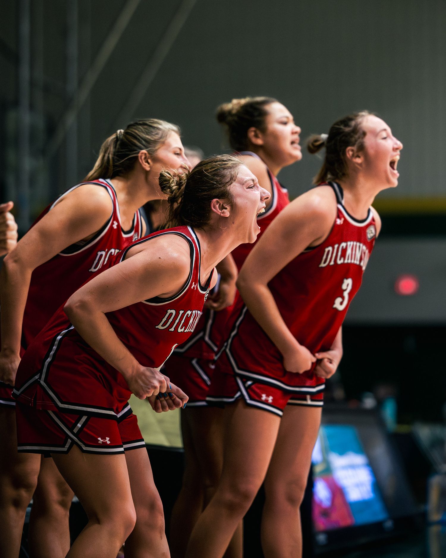 Basketball cheerleaders in red uniforms cheering enthusiastically from the sidelines during a game.