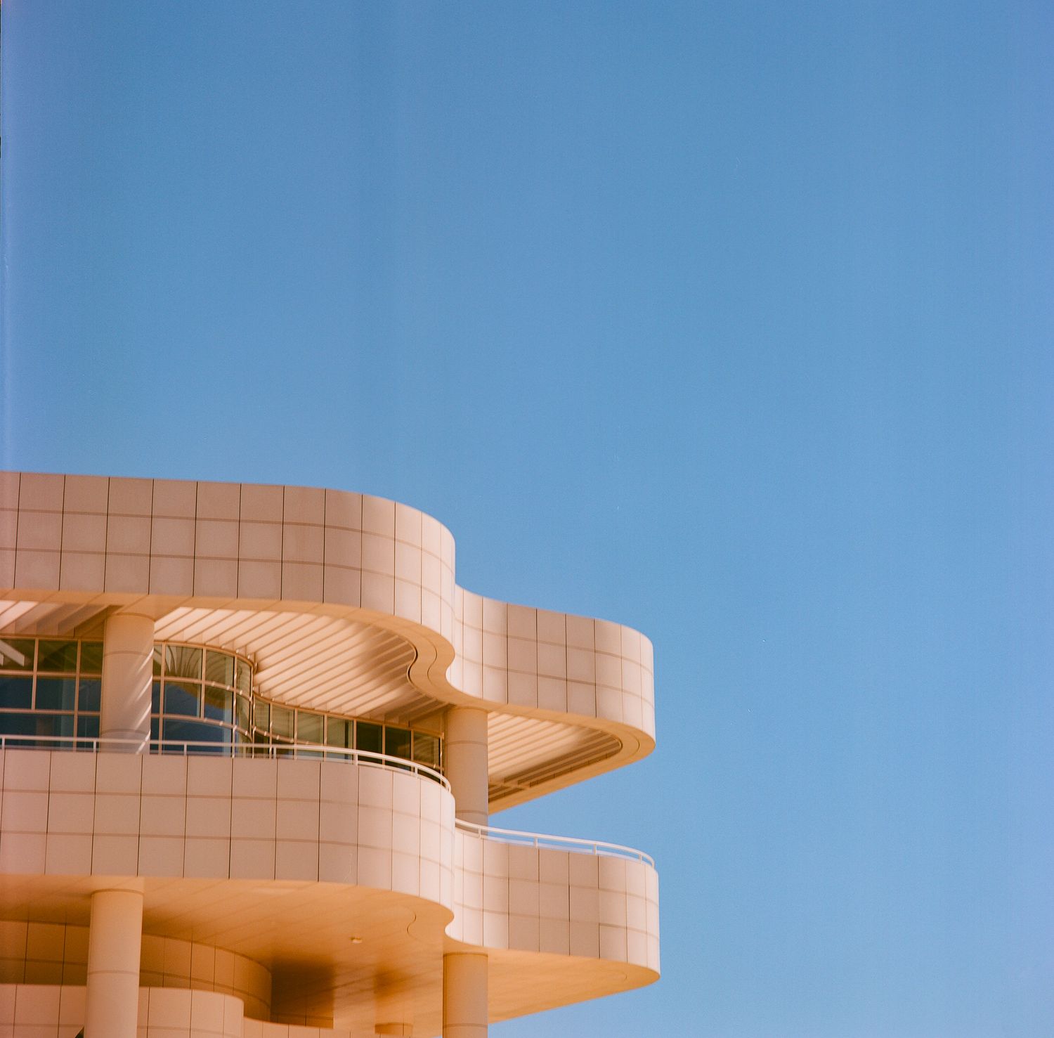 Modern curved architecture building with white geometric balconies against blue sky.
