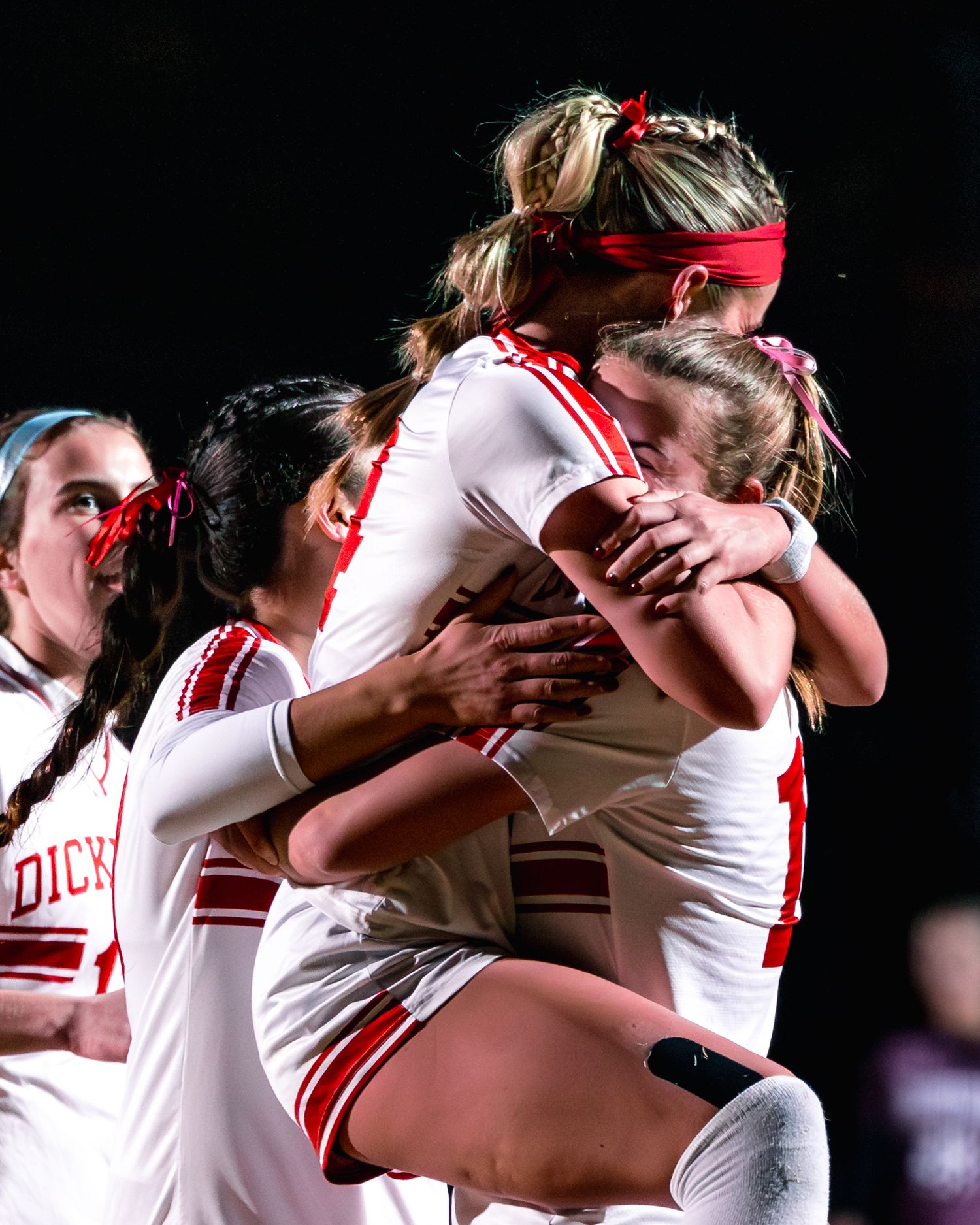 Soccer players celebrate and embrace emotionally after a match victory.