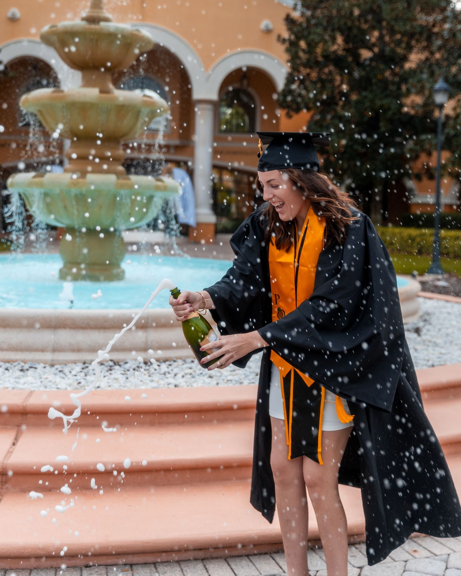 A person in a black jacket splashes water in a playful sequence at a pool or water feature.