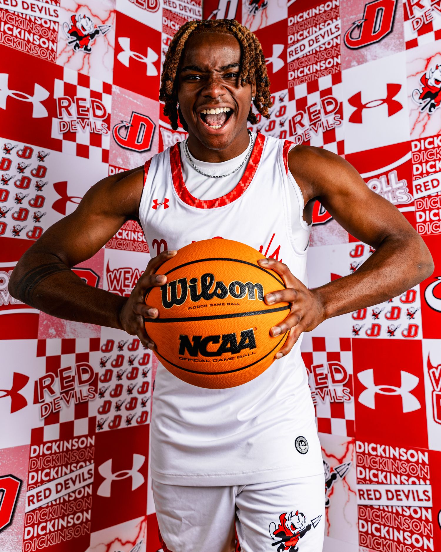 Basketball players pose playfully with Wilson and NCAA basketballs against a red and white Under Armour backdrop.