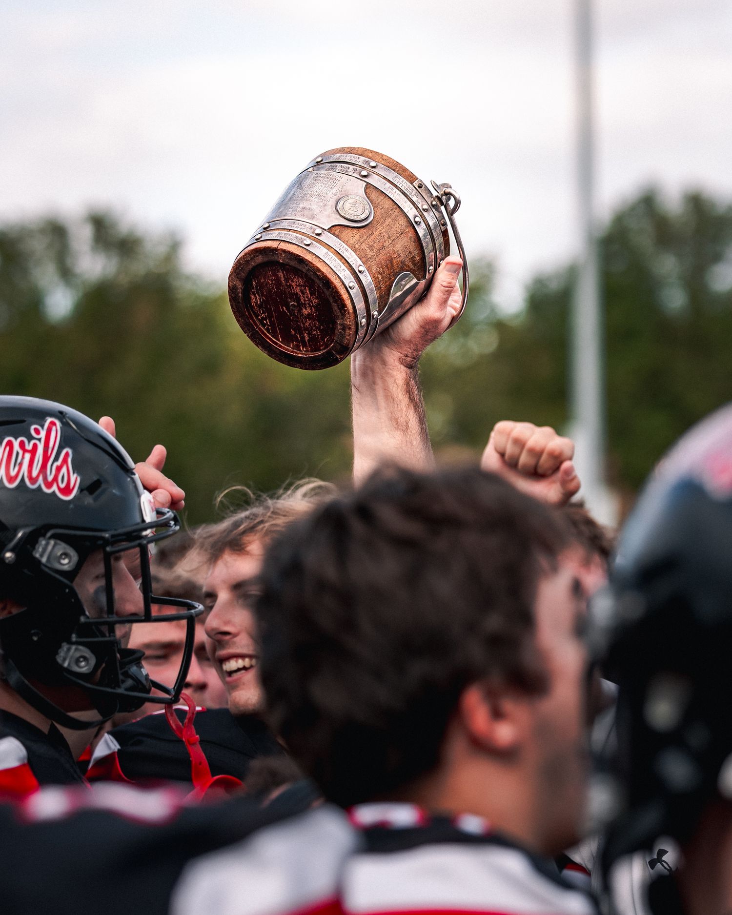 Football players celebrate with the game ball raised high during an outdoor sports match.