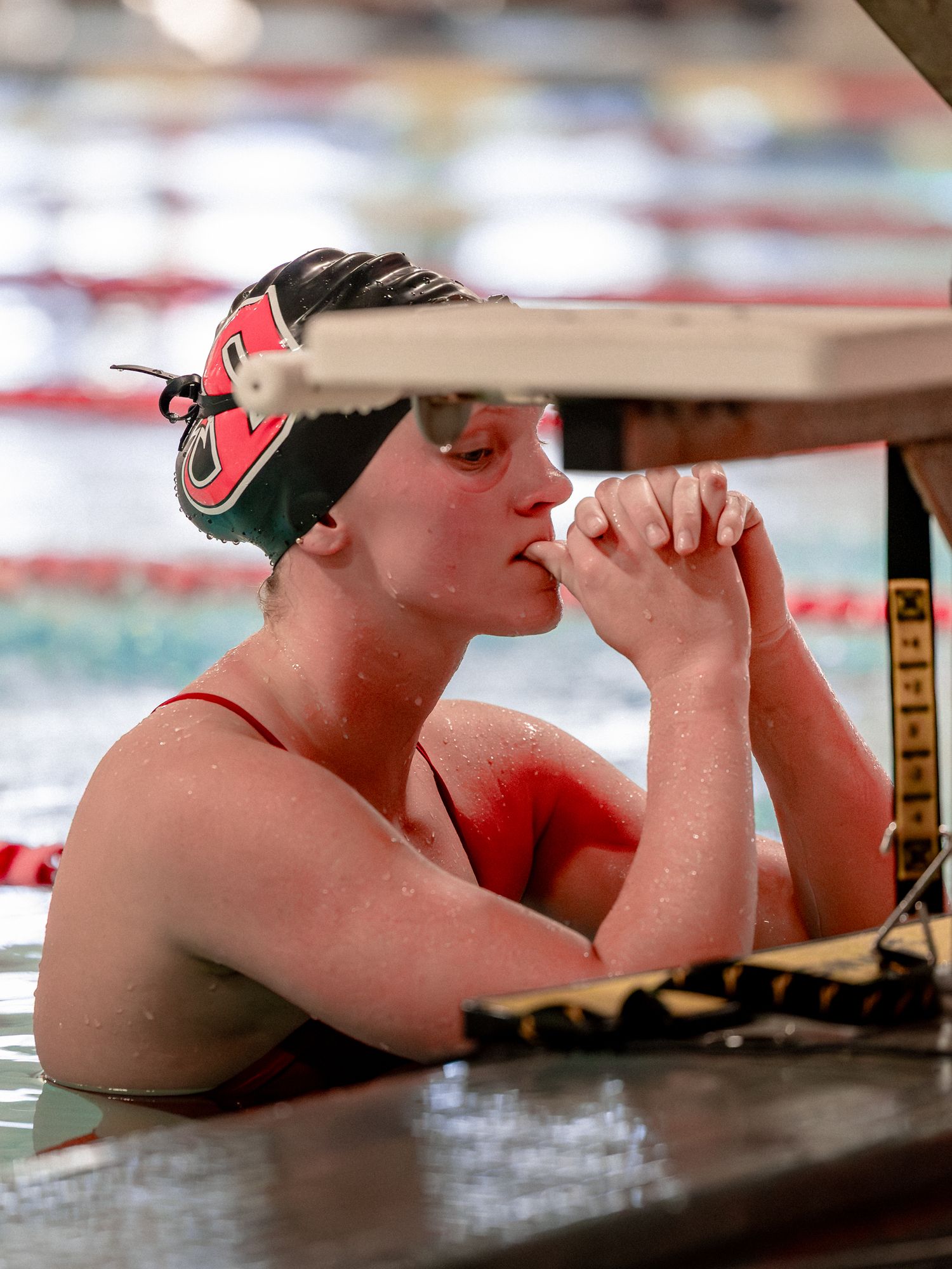 A swimmer rests their head on the edge of a pool during training or competition.