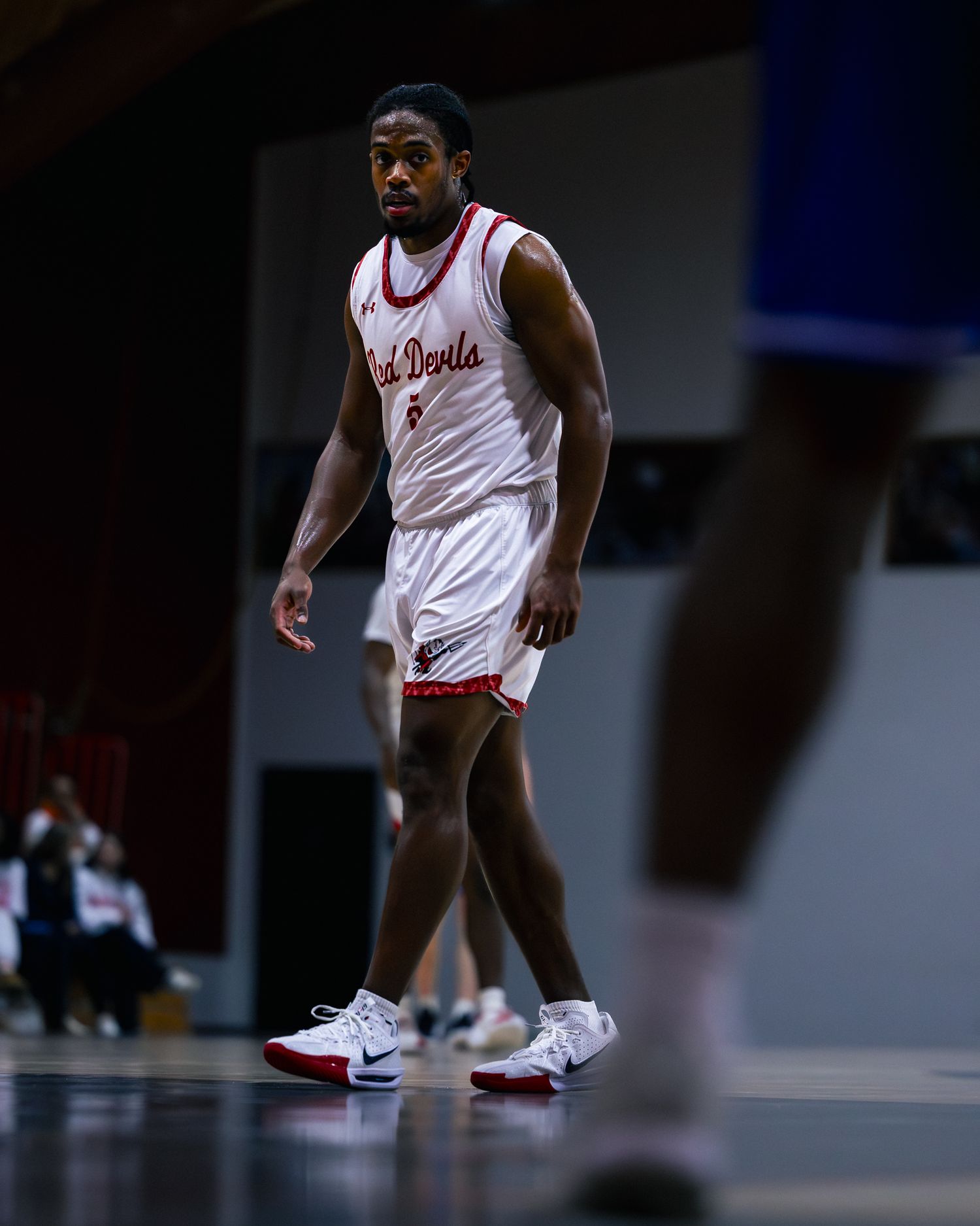 Close-up view of basketball players' feet in white and red sneakers on a court during a game.