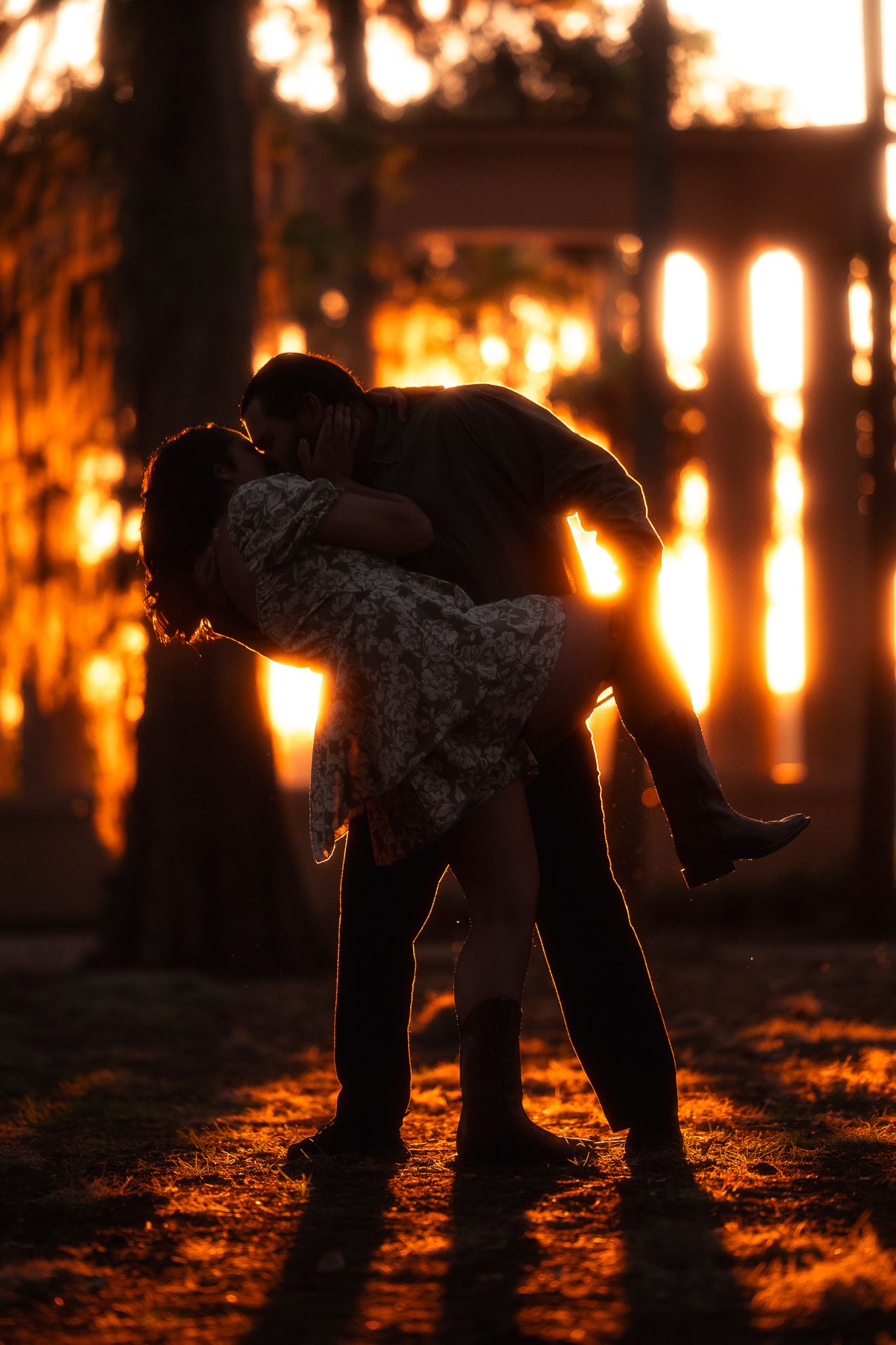 Silhouetted couple shares a romantic dip pose against a golden sunset backdrop.