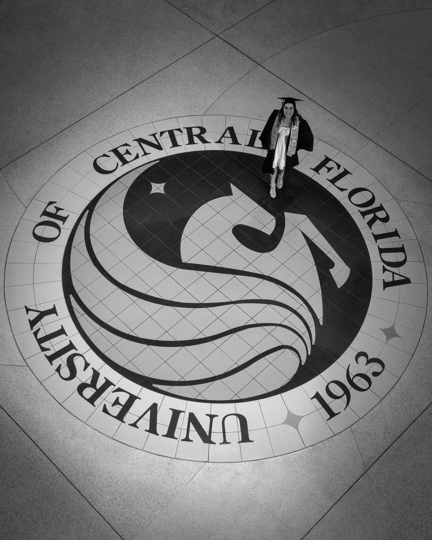 A series of black and white photos showing fragments of a decorative circular floor design with curved text and patterns.