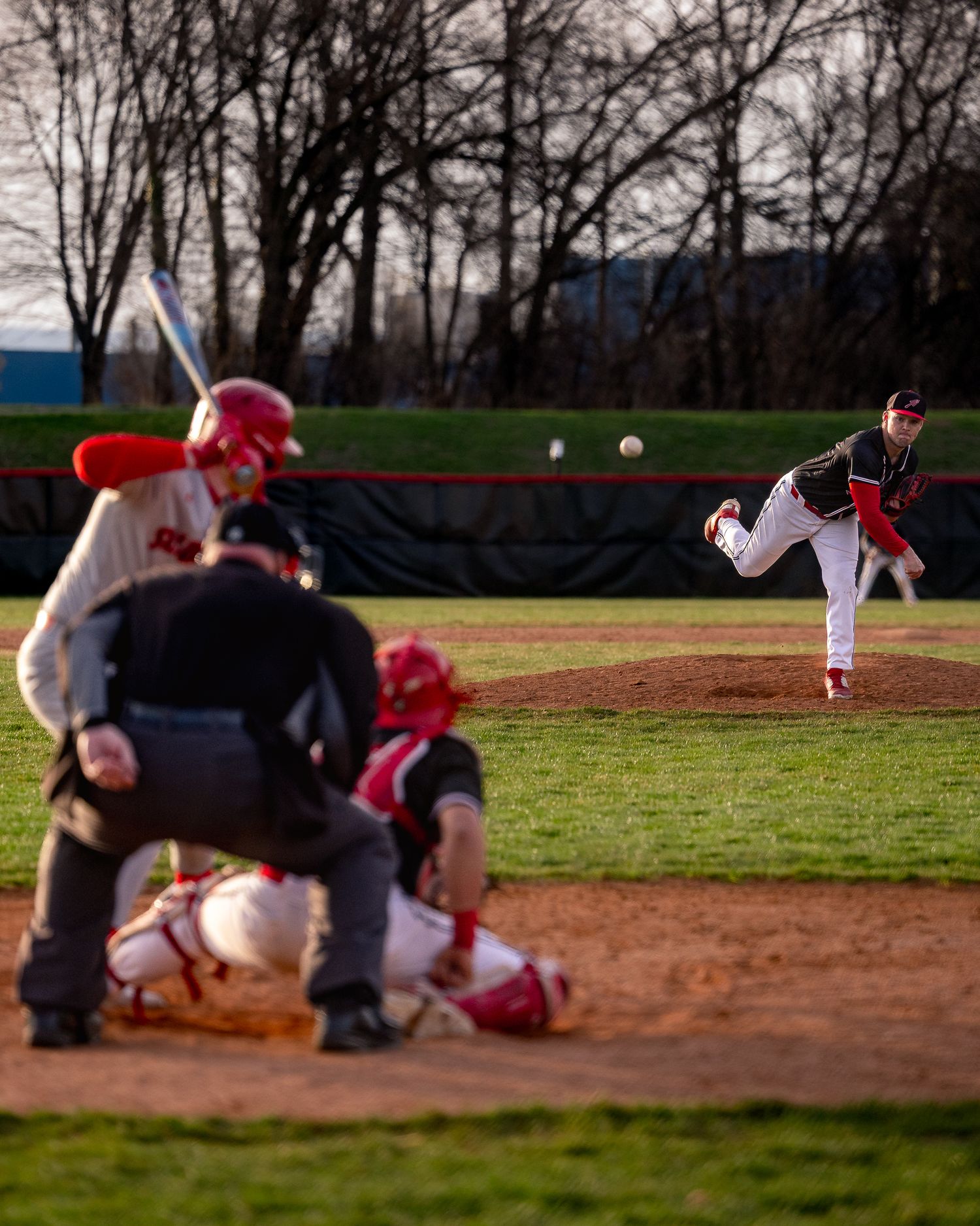 Baseball players slide into base during an intense play at a baseball game on a dirt infield.