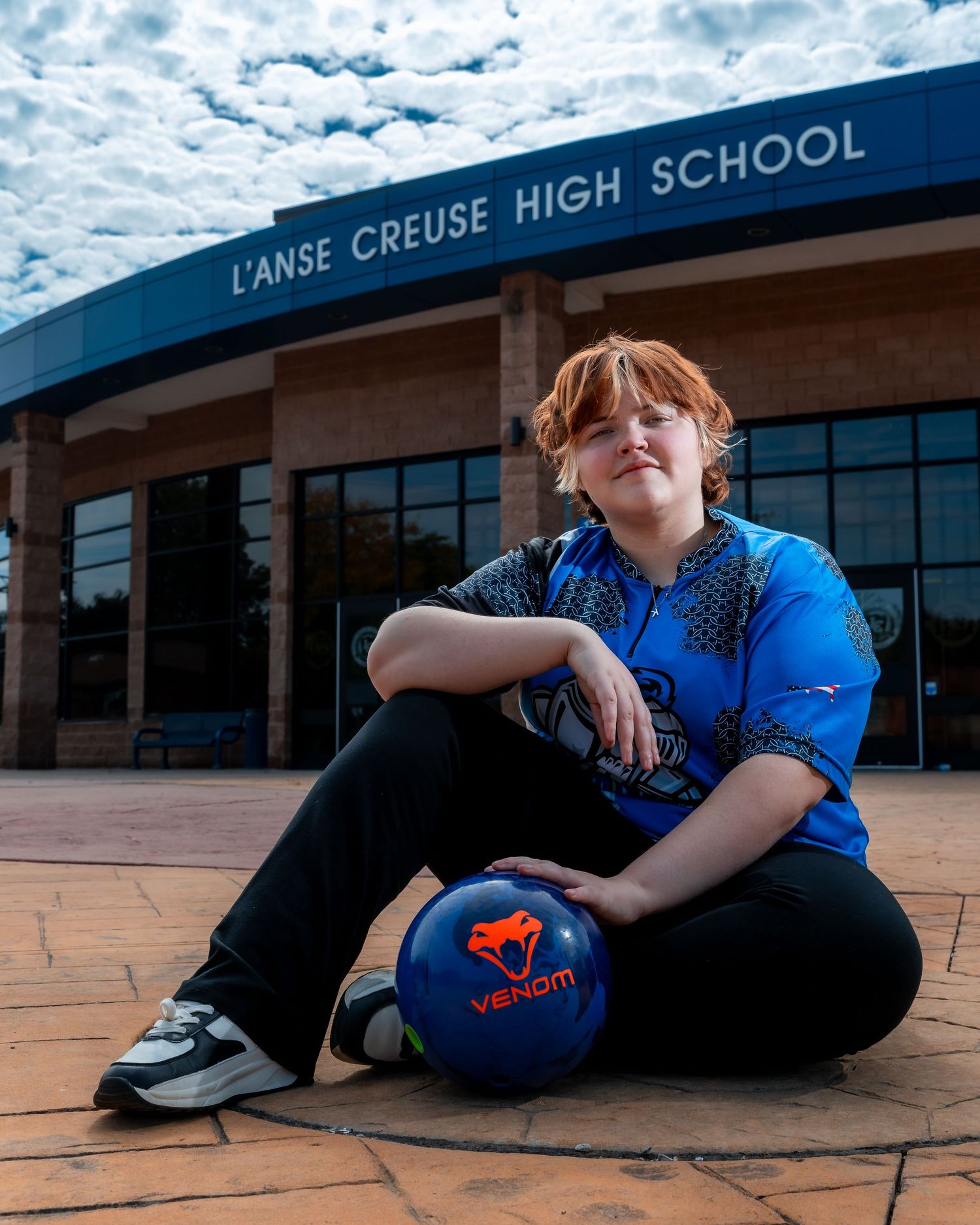 Student relaxing outside L'Anse Creuse High School on a cloudy day.