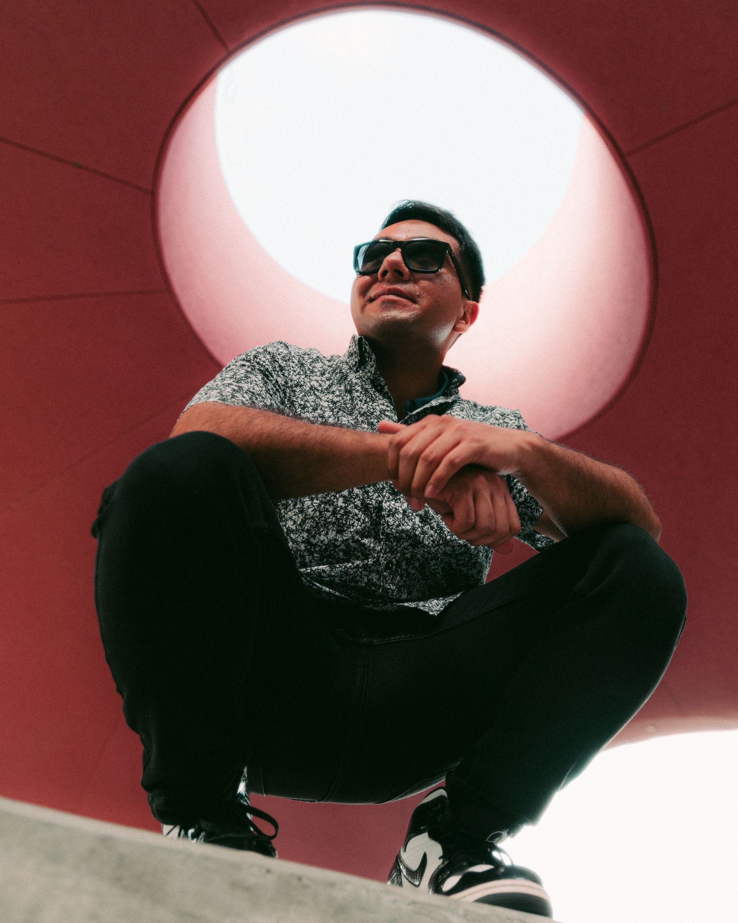 A series of low-angle shots showing someone in sunglasses and dark clothing against a pink-tinted ceiling with dramatic lighting.