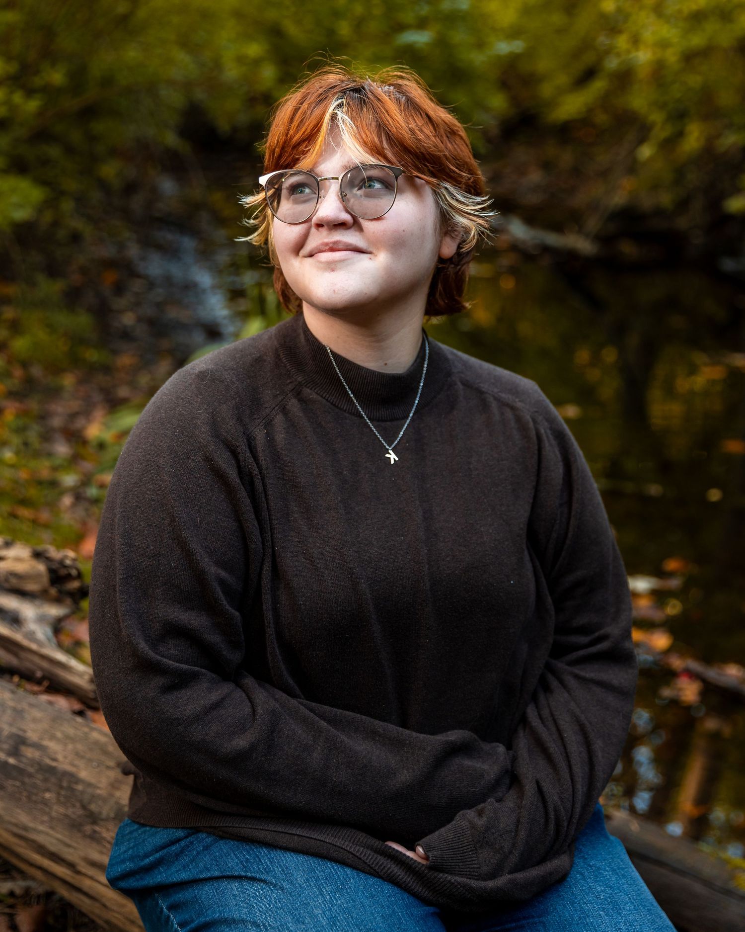 Casual outdoor portrait session featuring someone in a black sweater against an autumn background.