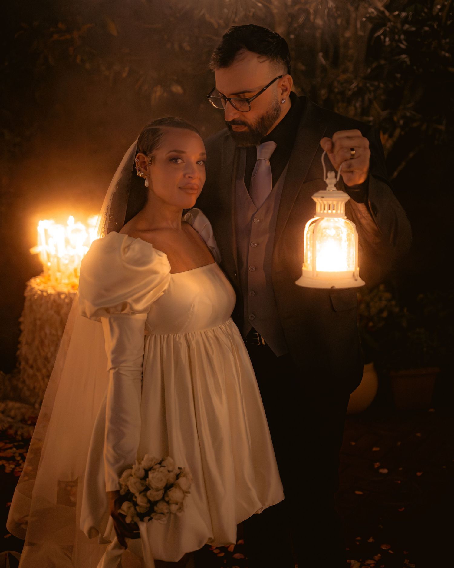 A romantic nighttime wedding photoshoot with lanterns creating a warm atmospheric glow in the darkness.