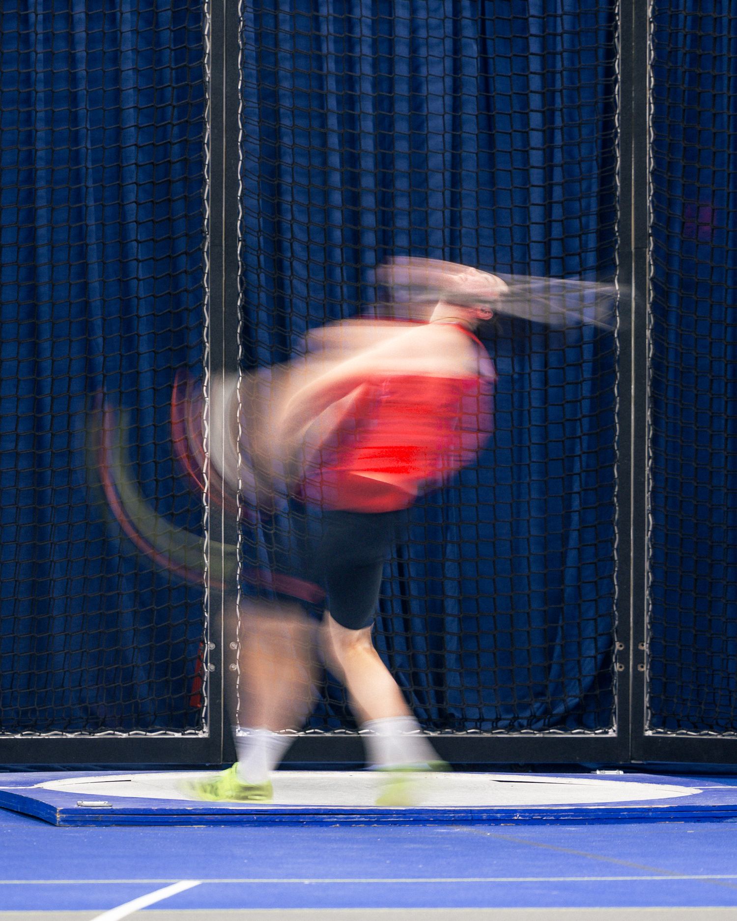 Tennis player in motion captured in a blurred sequence showing dynamic movement on a blue court surface.