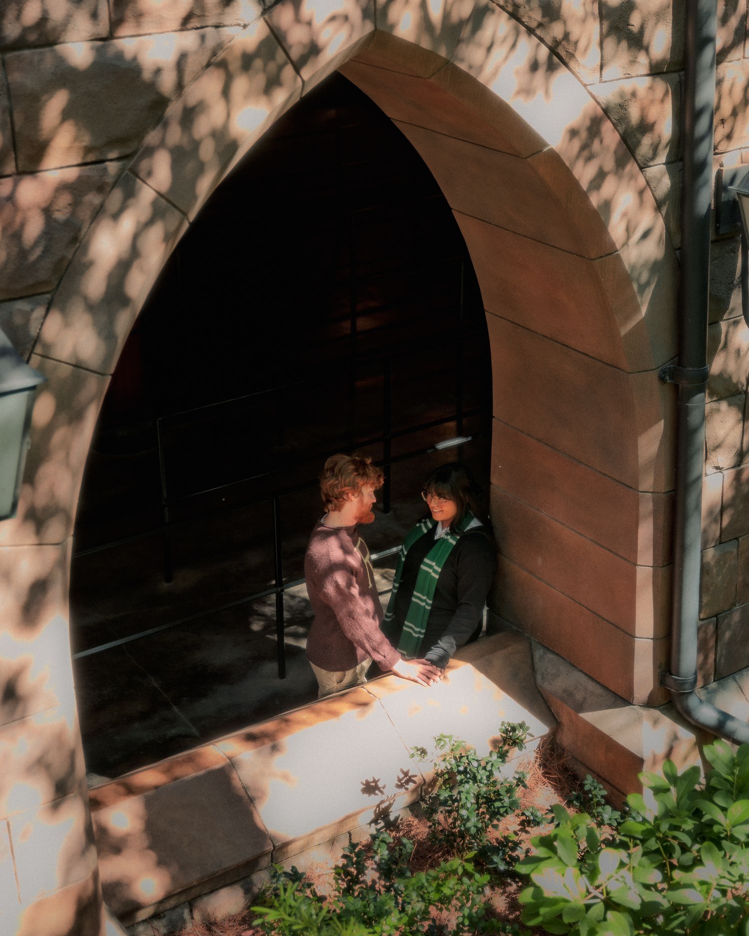Two people sit together in a cozy arched doorway alcove while dappled shadows play across the scene.