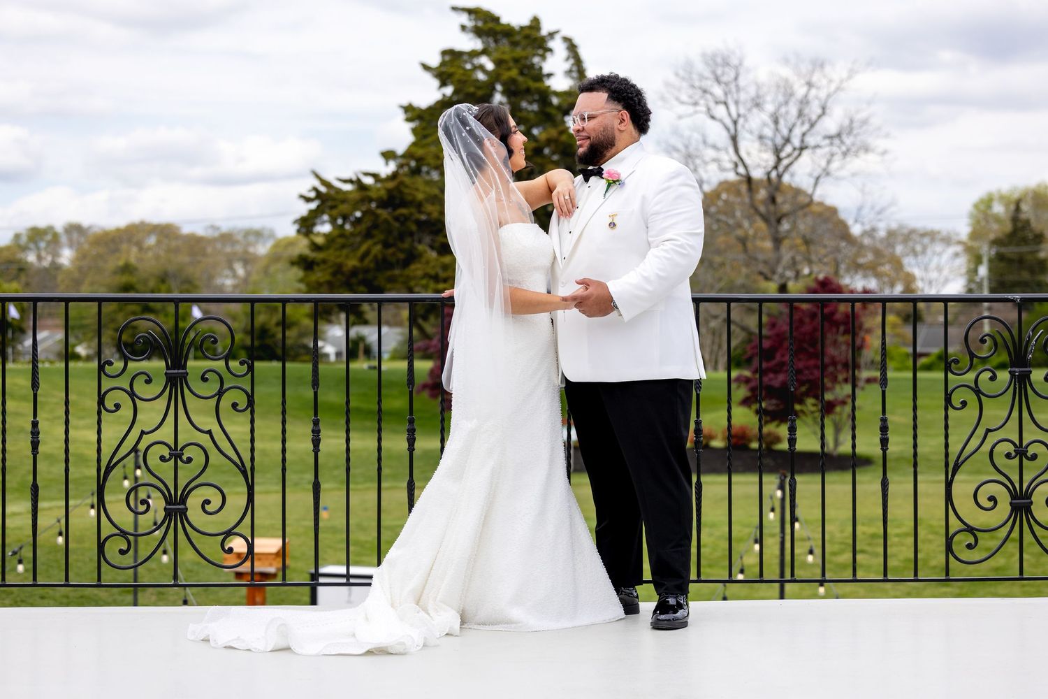 Bride and groom share a romantic dance on an outdoor terrace with lush green gardens in the background.