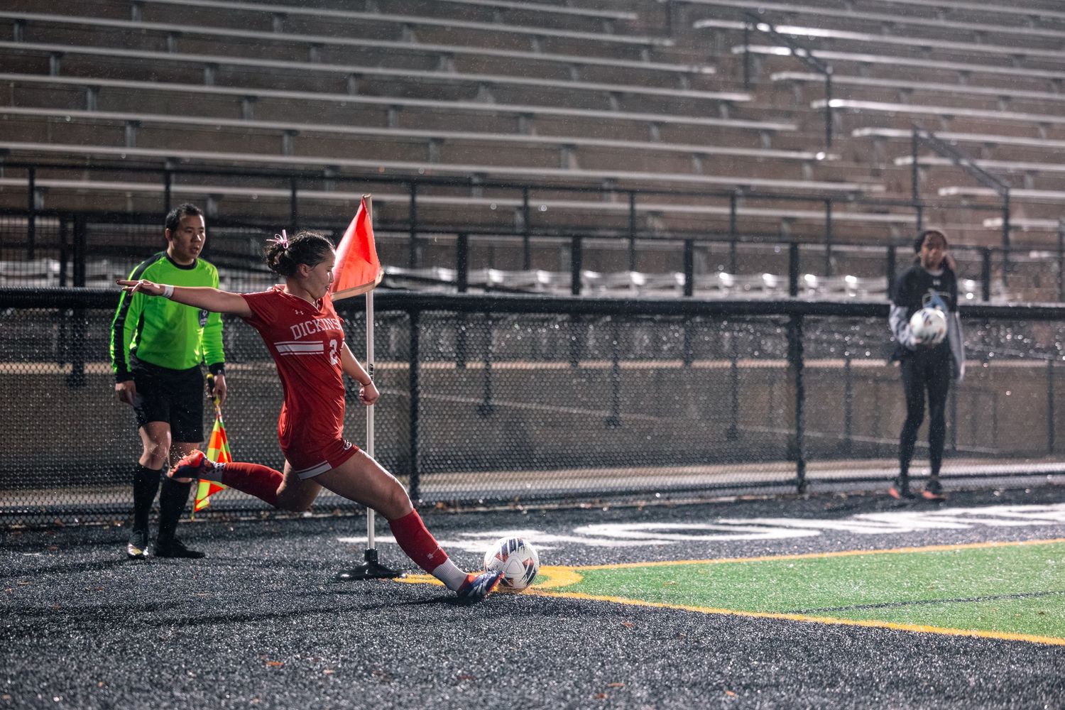 Dickinson soccer player taking a corner kick during a night set piece in the rain.