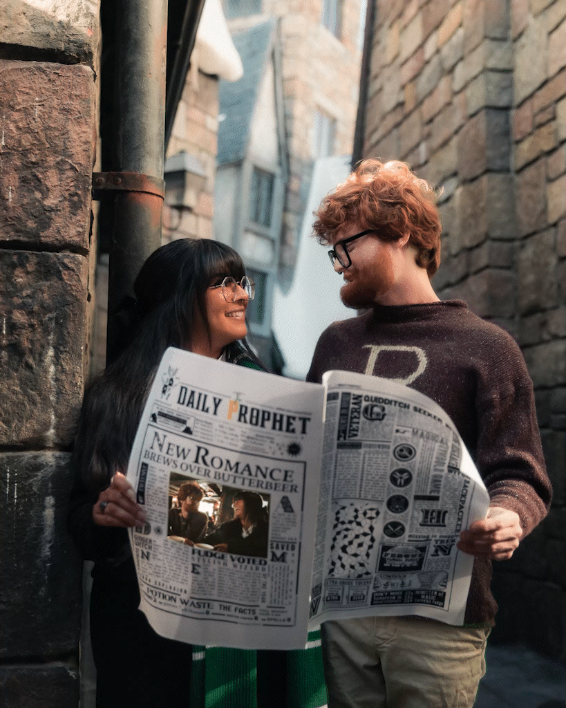 Two people read a newspaper together while standing against a brick wall in an alley.