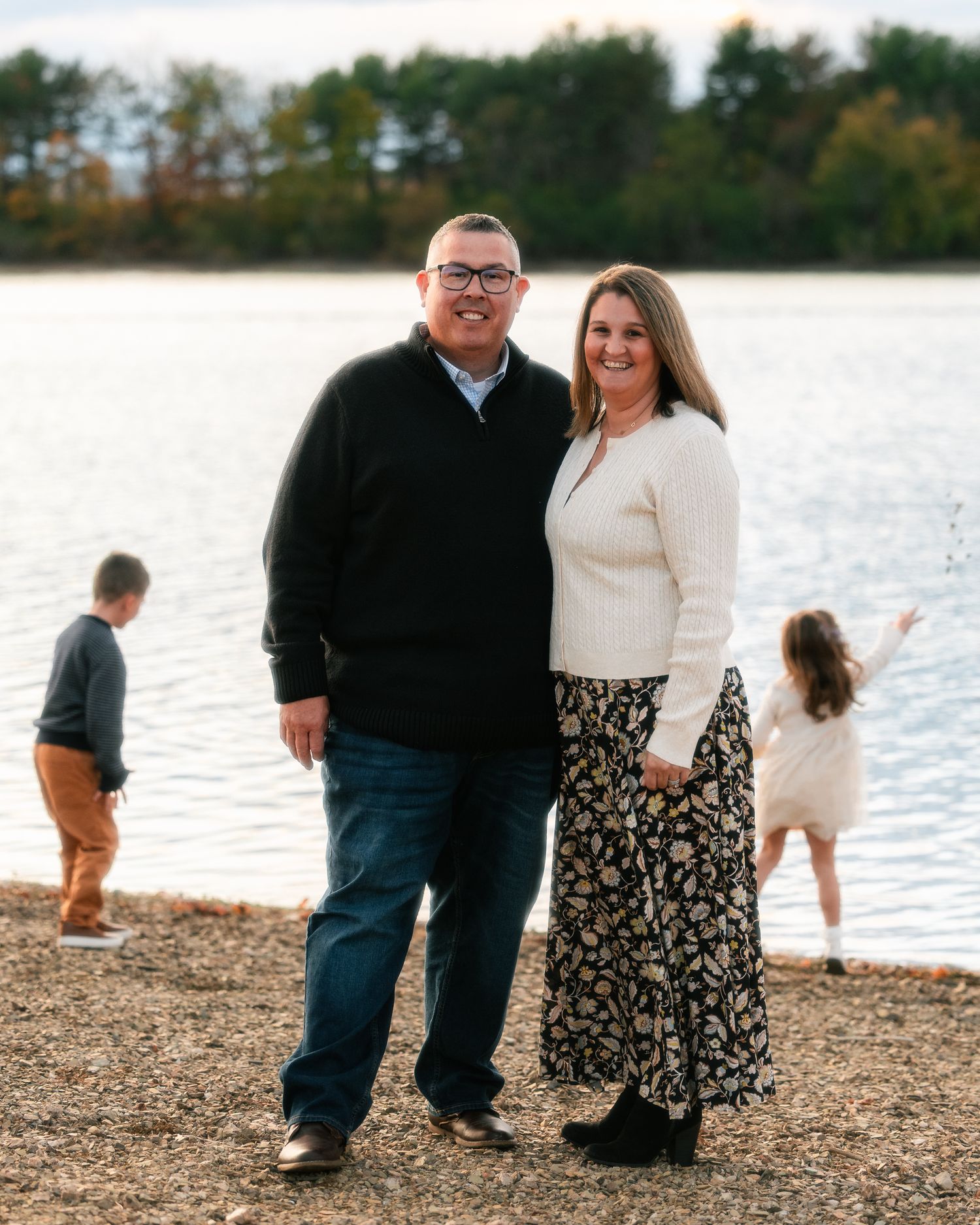 Family enjoying a casual moment together on a rocky beach by the water at sunset.