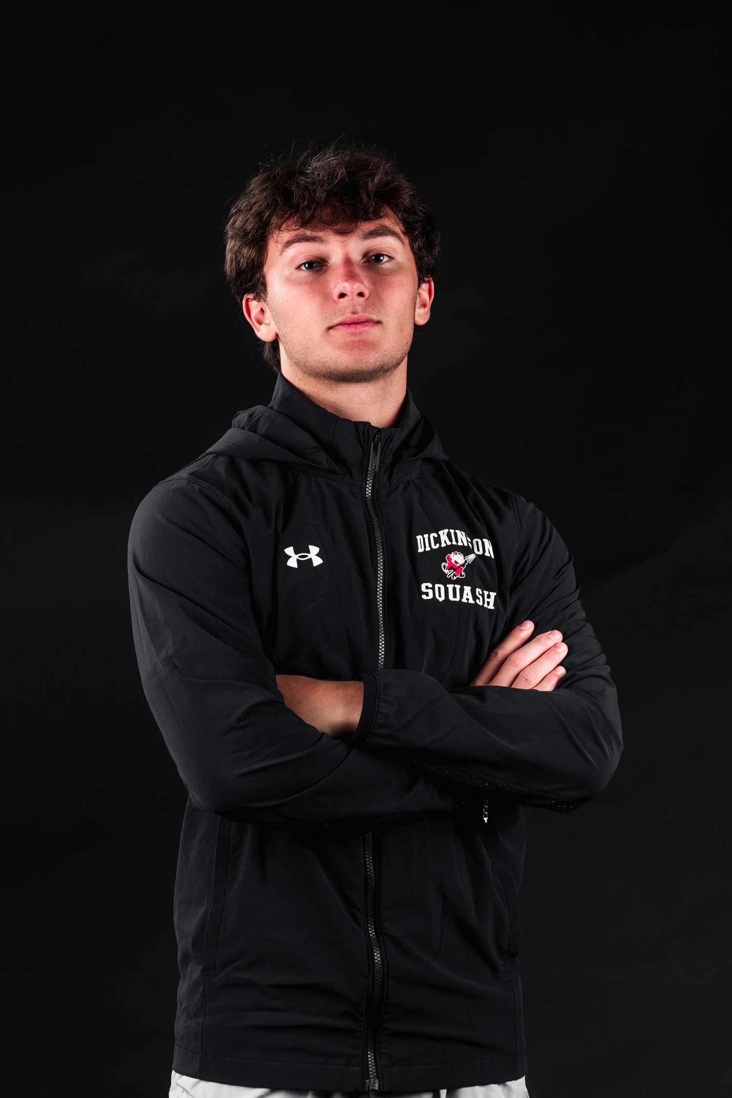 Person wearing black Under Armour jacket poses against dark background in series of dramatic athletic portraits.