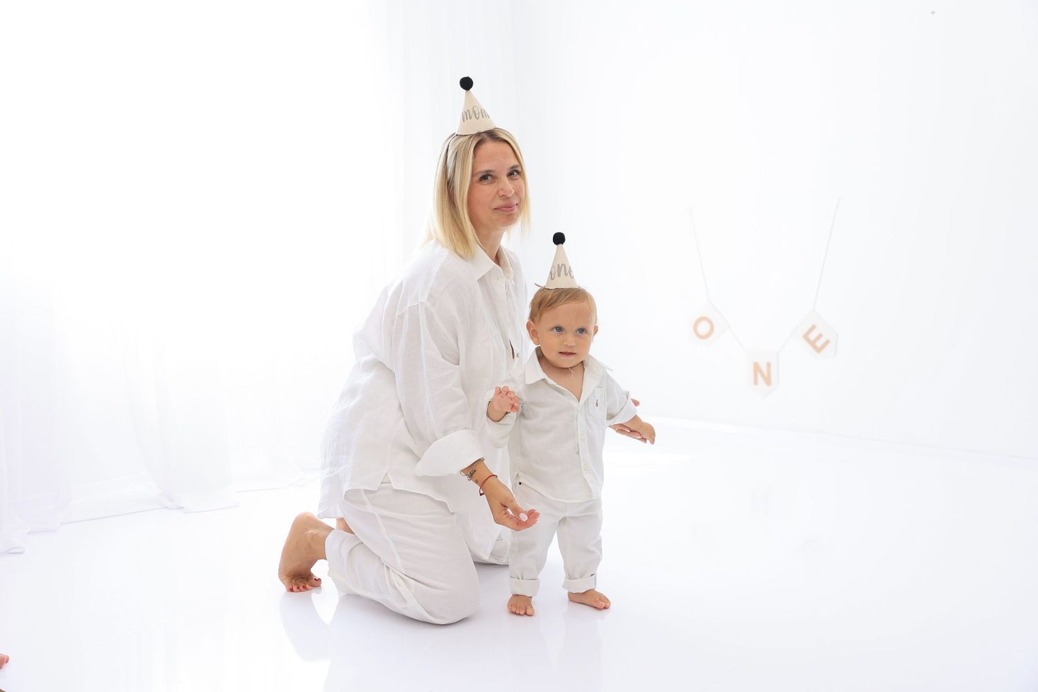 Family in all-white clothing plays together on clean white background during photo session. Dubai Photographer